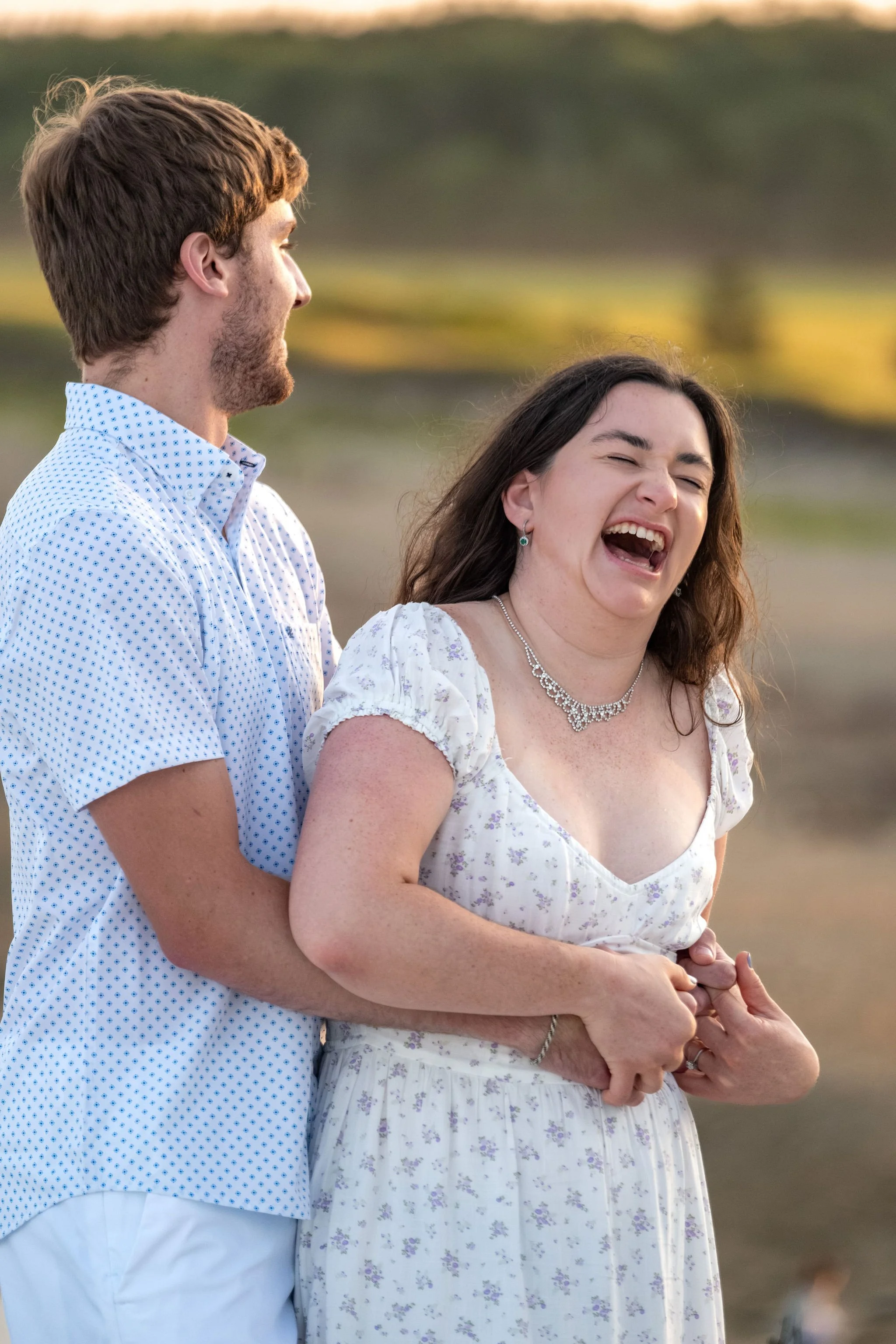 Kirstie laughing with her eyes closed while Lucas holds her above the beach at Reid State Park in Georgetown Maine engagement photography VMG Productions