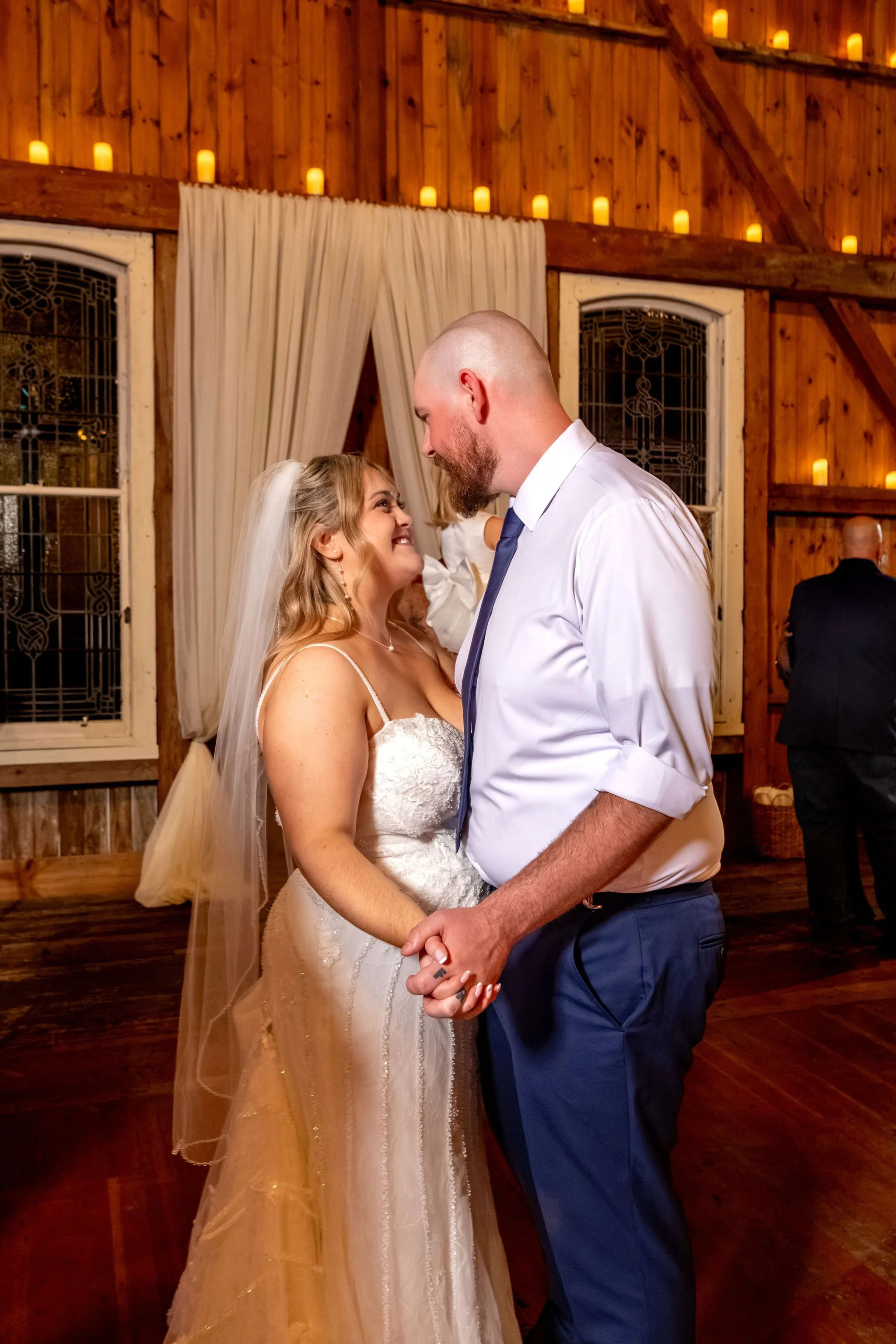 Ellie and Sam holding hands and smiling at each other during a slow dance in the barn at Boothbay Playhouse in Boothbay Maine fall wedding photography VMG Productions