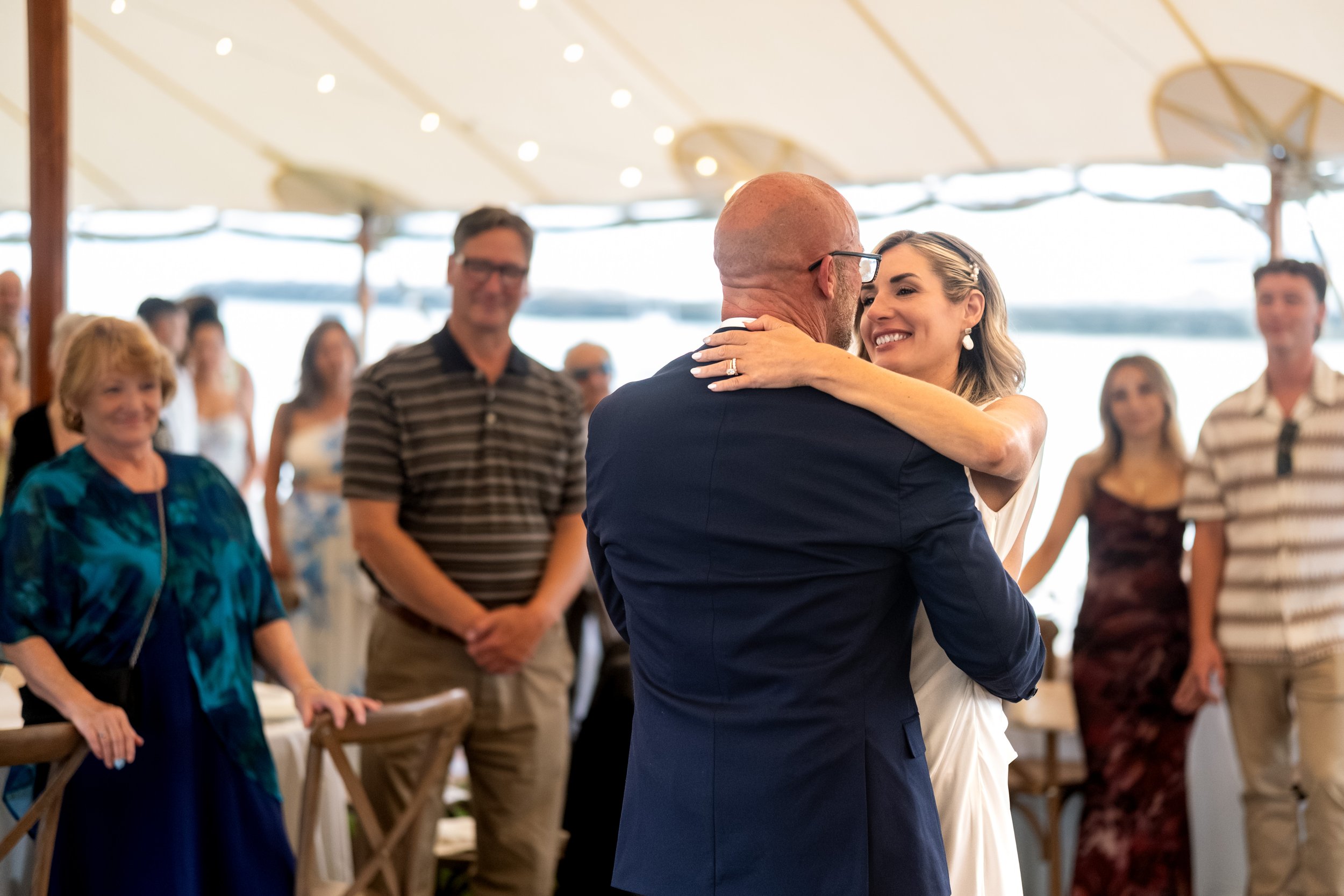 Ashley and Marc Draper dancing close surrounded by their guests under the tent at The Breakwater Inn in Kennebunkport Maine summer wedding photography VMG Productions