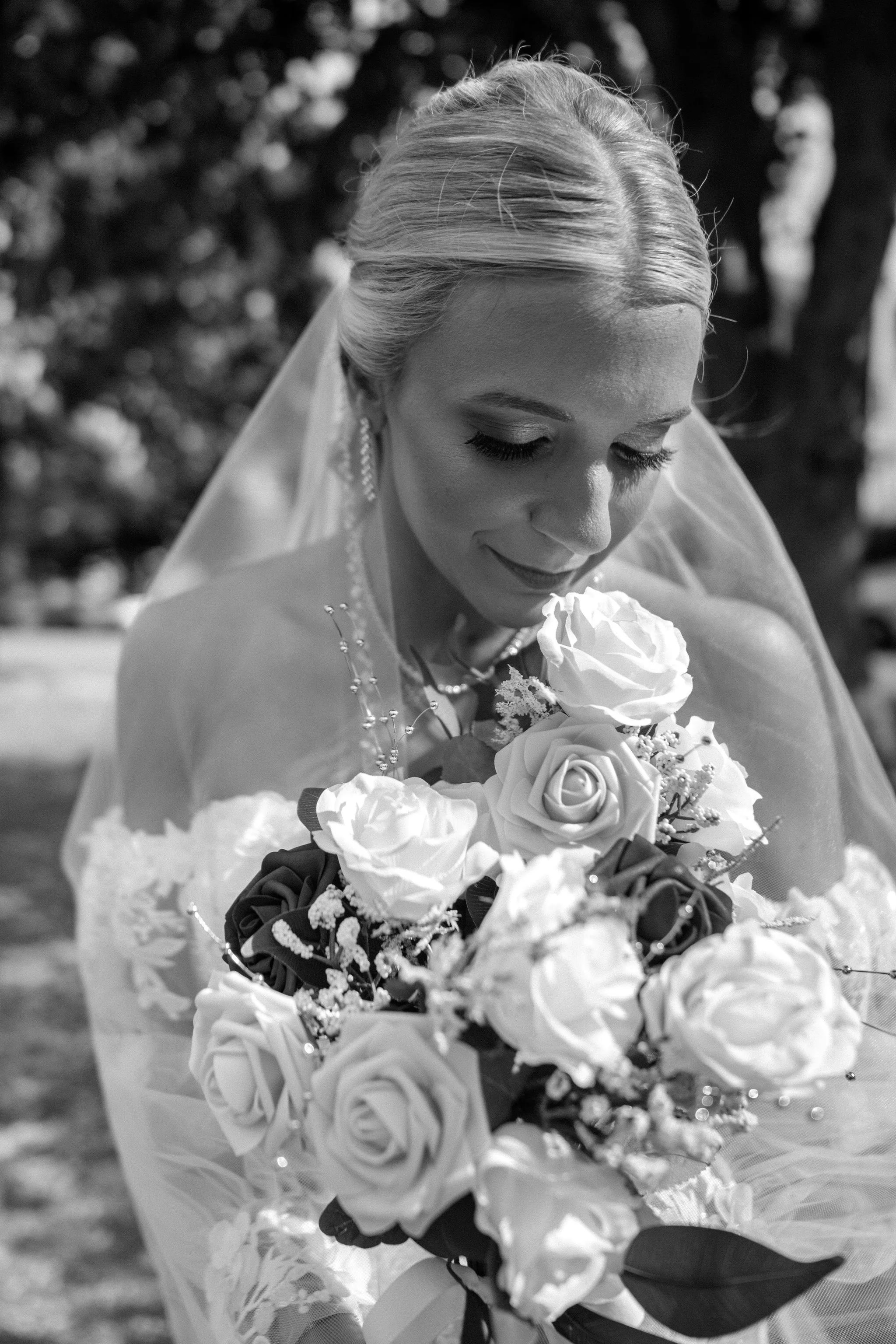 Jeremiah and Vienna bride stands alone showing full gown and veil train beneath flowering trees at Eastern Promenade Portland Maine spring wedding photography VMG Productions