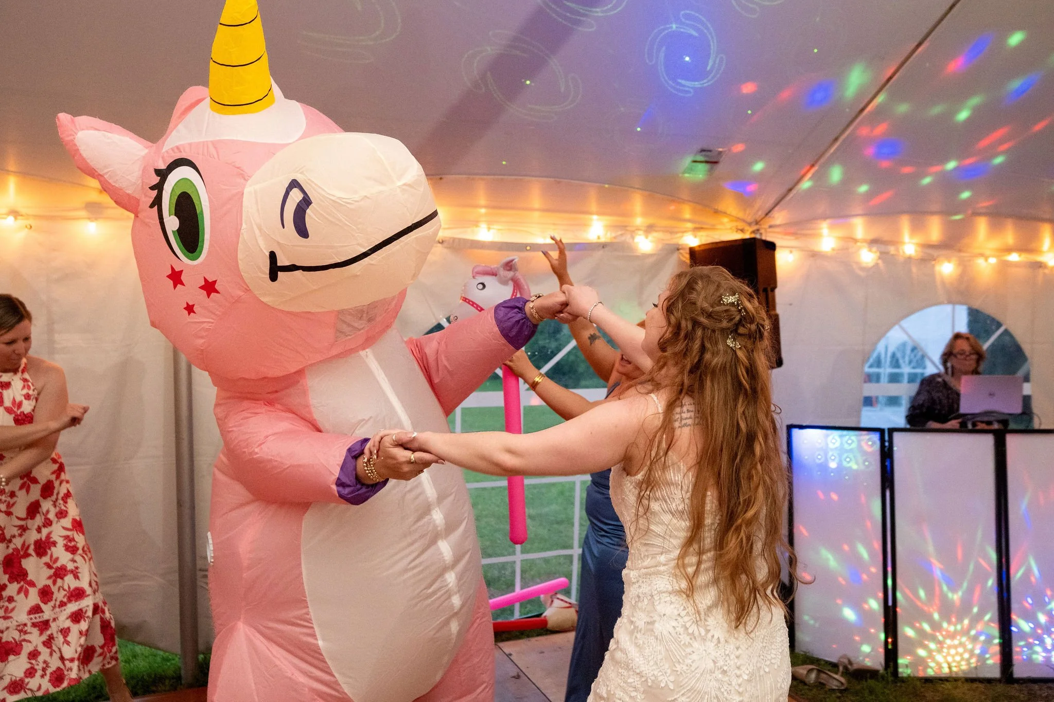 Kayla DeAngelis dancing with an inflatable unicorn under the disco lights inside the reception tent at their Sanbornton New Hampshire wedding photography VMG Productions