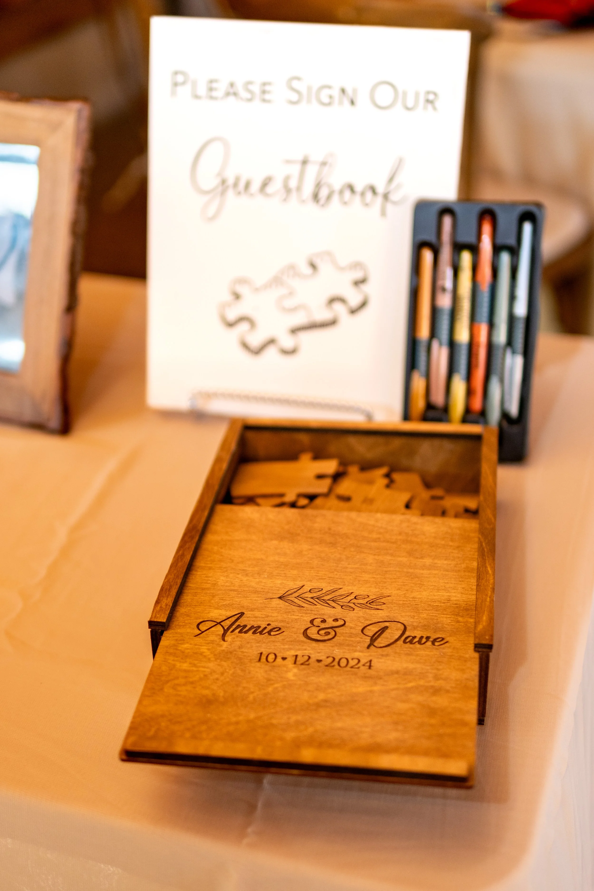 Laser engraved wooden puzzle box guest book reading Annie and Dave 10-12-2024 with individual wooden puzzle pieces for guests to sign at Golden Pine Farm and Wedding Barn Maine fall wedding