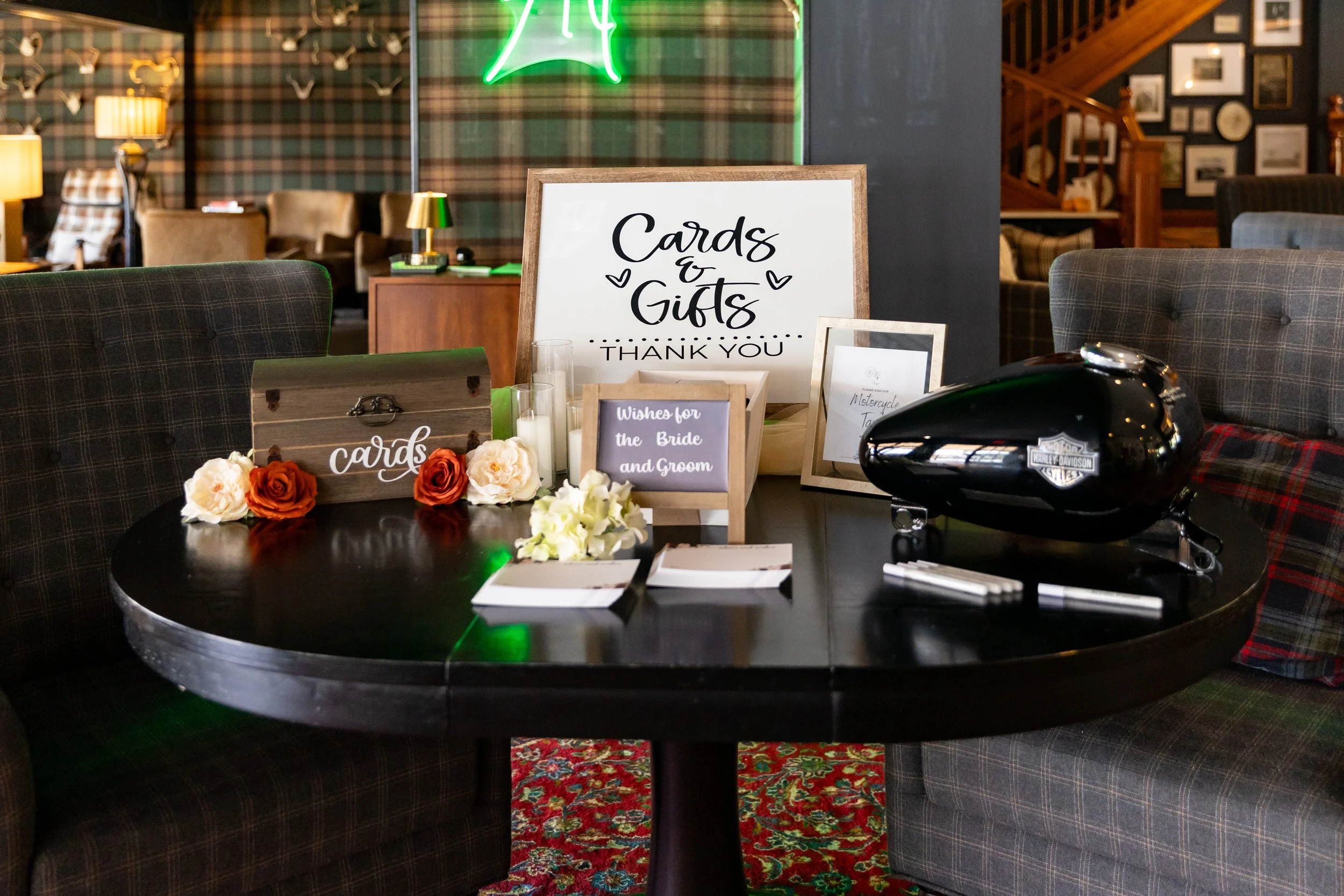 Cards and gifts table at Wentworth Inn Jackson New Hampshire wedding 2024 featuring black Harley Davidson motorcycle tank as wedding guest book with acrylic paint markers roses and framed sign