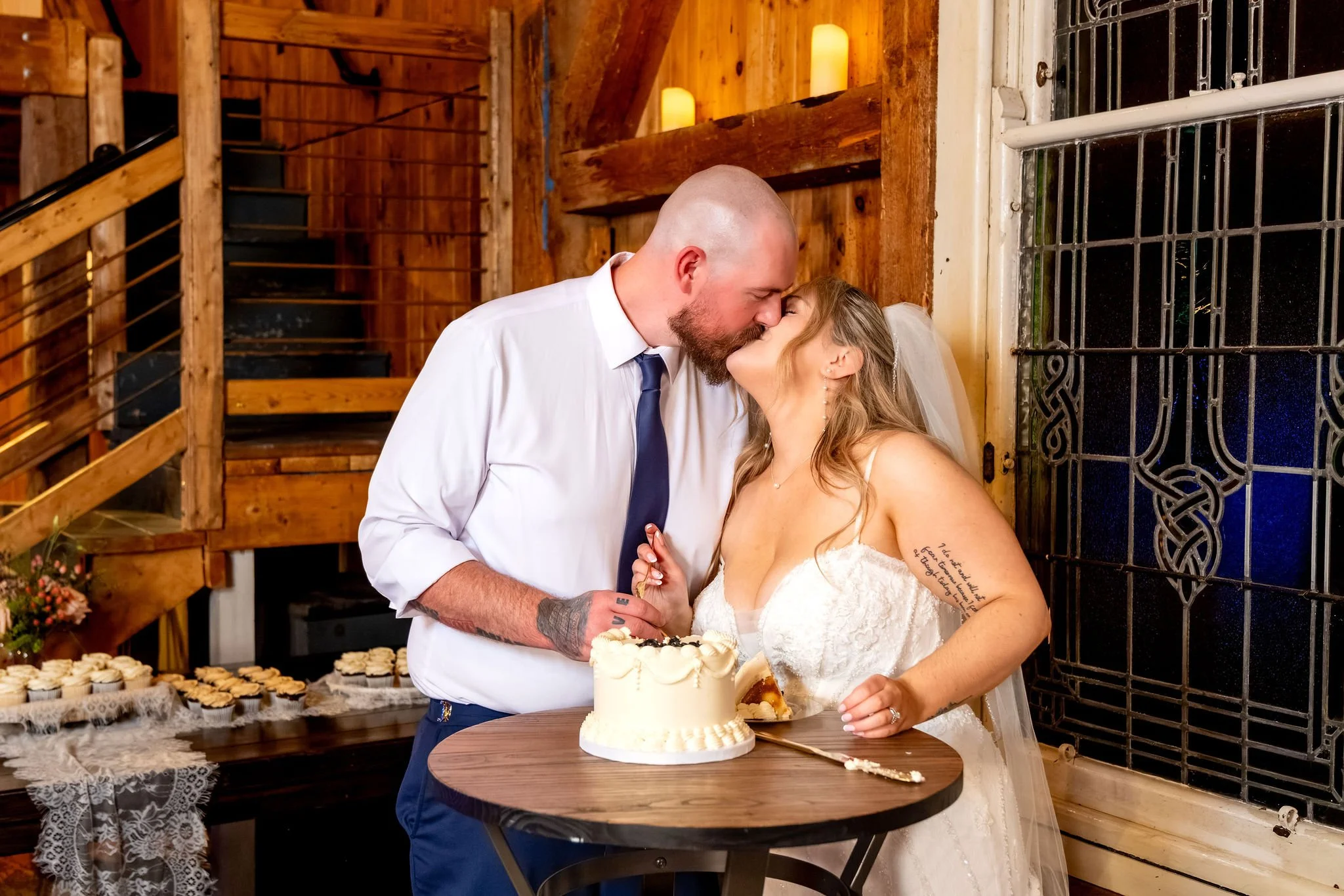 Ellie and Sam kissing as they finish cutting the cake at Boothbay Playhouse in Boothbay Maine fall wedding photography VMG Productions