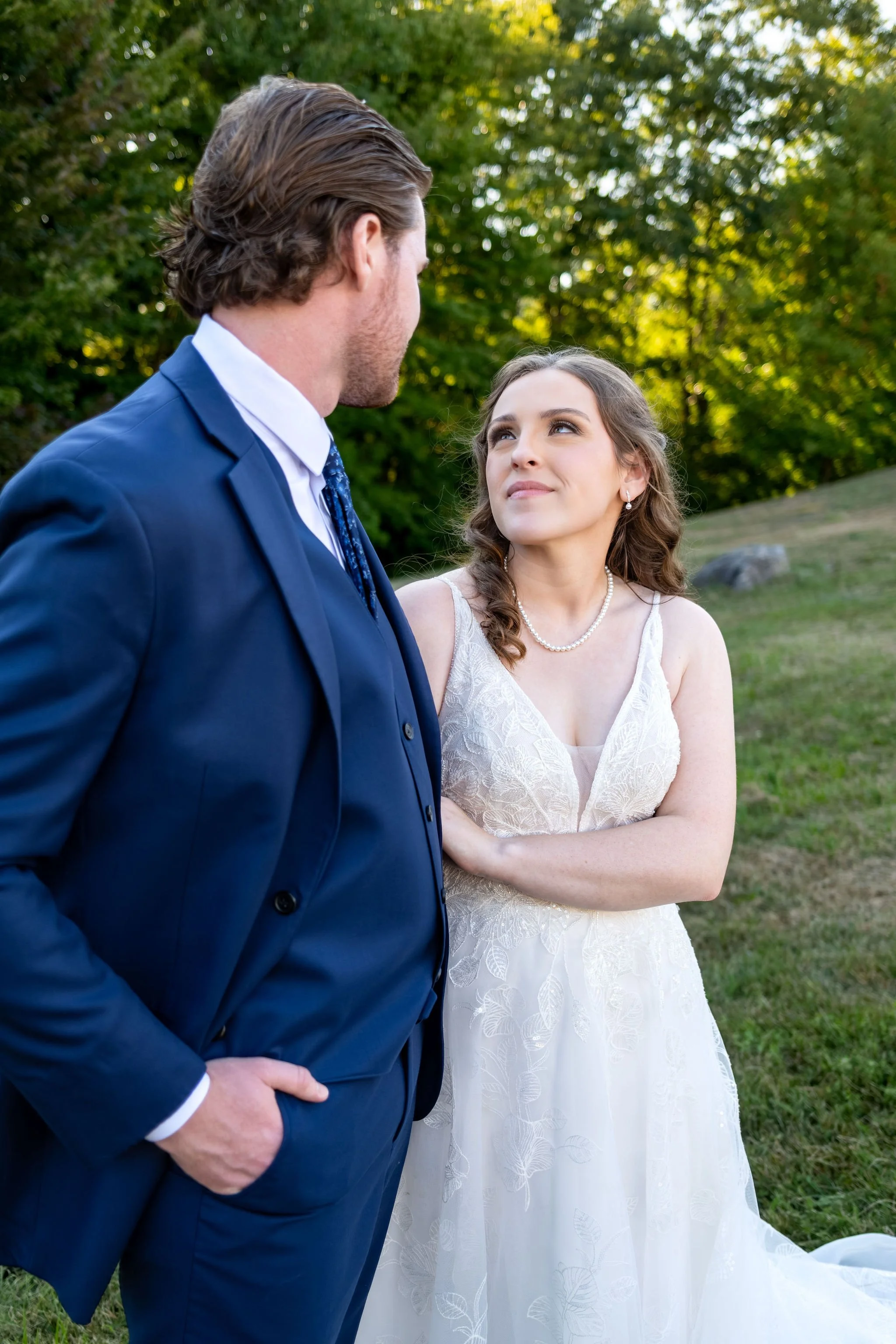Hollie looking up at Zachary with her hand on his chest in the field at golden hour at The Lucerne Inn in Dedham Maine summer wedding photography VMG Productions