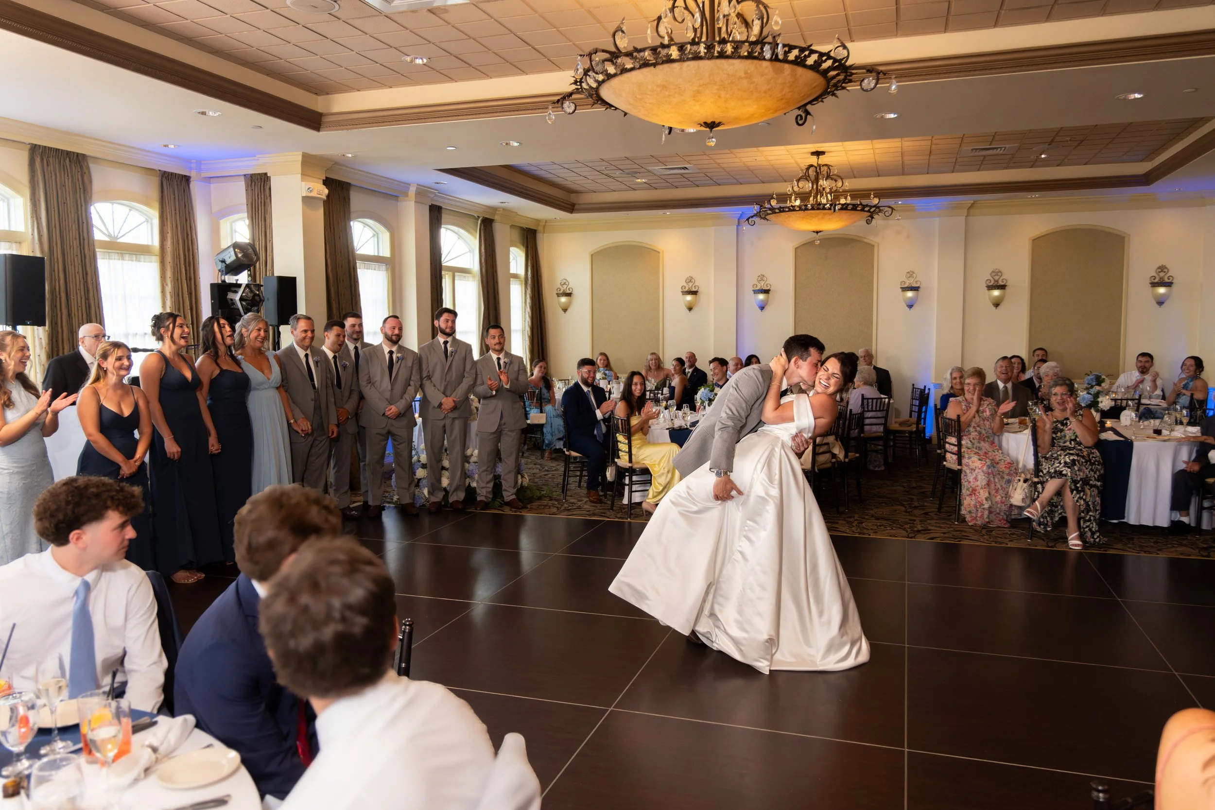 Anthony Pirolli dipping Caroline for a kiss during their first dance as the wedding party and guests watch at Union Bluff Hotel in York Maine wedding photography VMG Productions