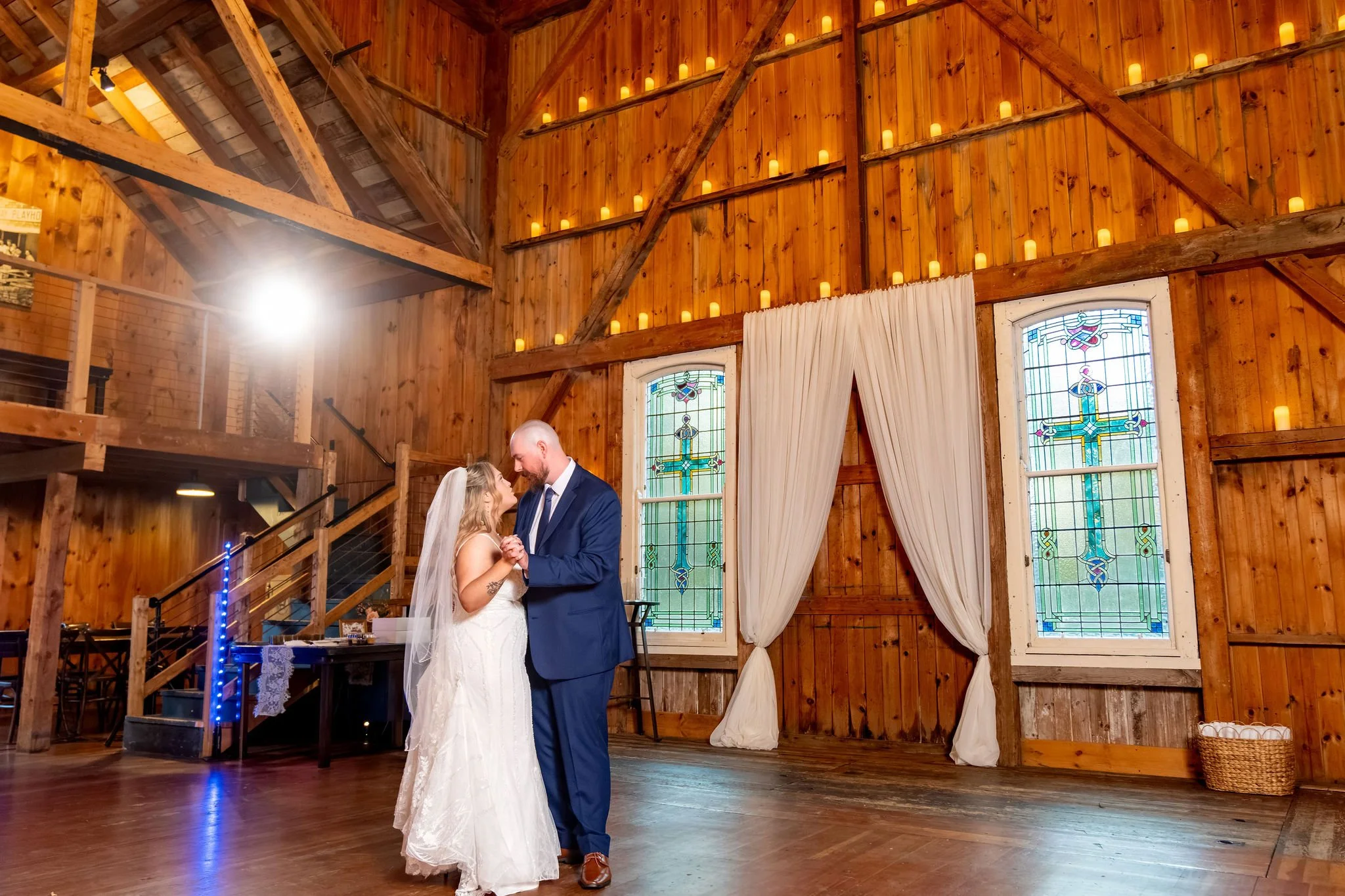 Ellie and Sam's first dance in the candlelit barn in front of the stained glass windows at Boothbay Playhouse in Boothbay Maine fall wedding photography VMG Productions