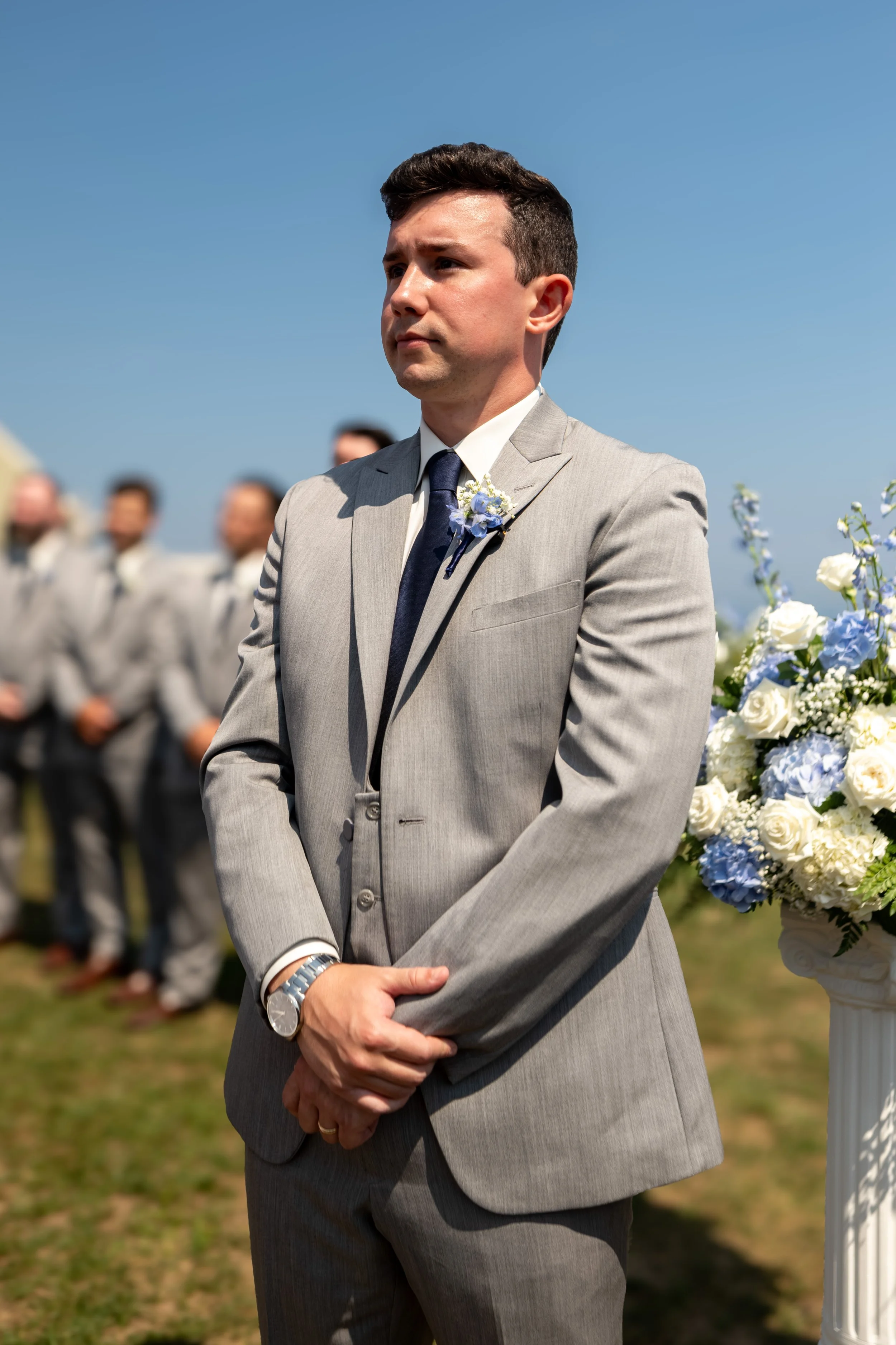Anthony Pirolli waiting at the front of the ceremony with his groomsmen and blue hydrangea boutonniere at Union Bluff Hotel in York Maine wedding photography VMG Productions