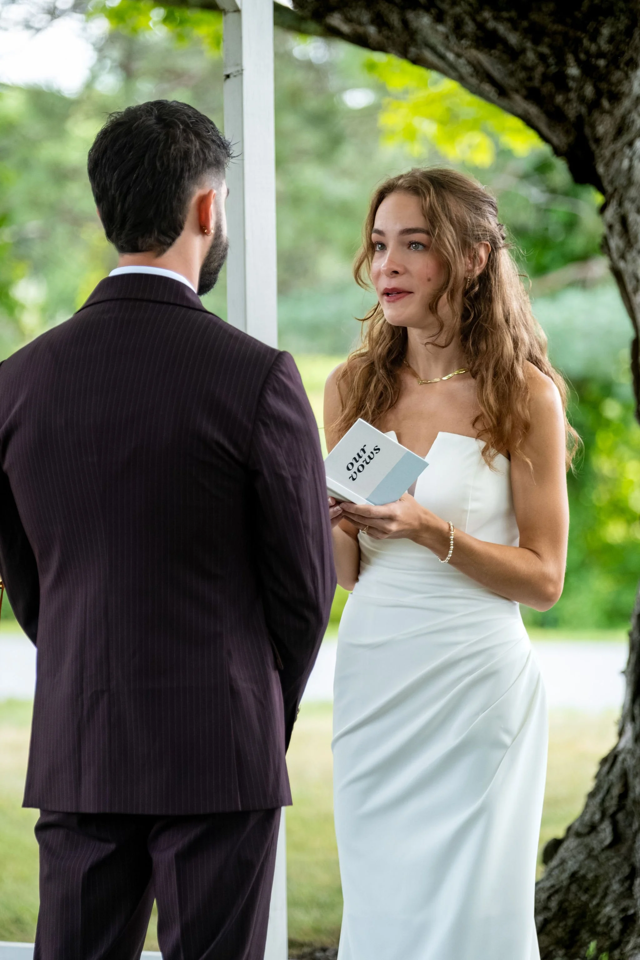 Cassidy Begin reading her vows from a small book to Chase at the arbor at Maple Hill Farm Inn and Conference Center in Hallowell Maine summer wedding photography VMG Productions