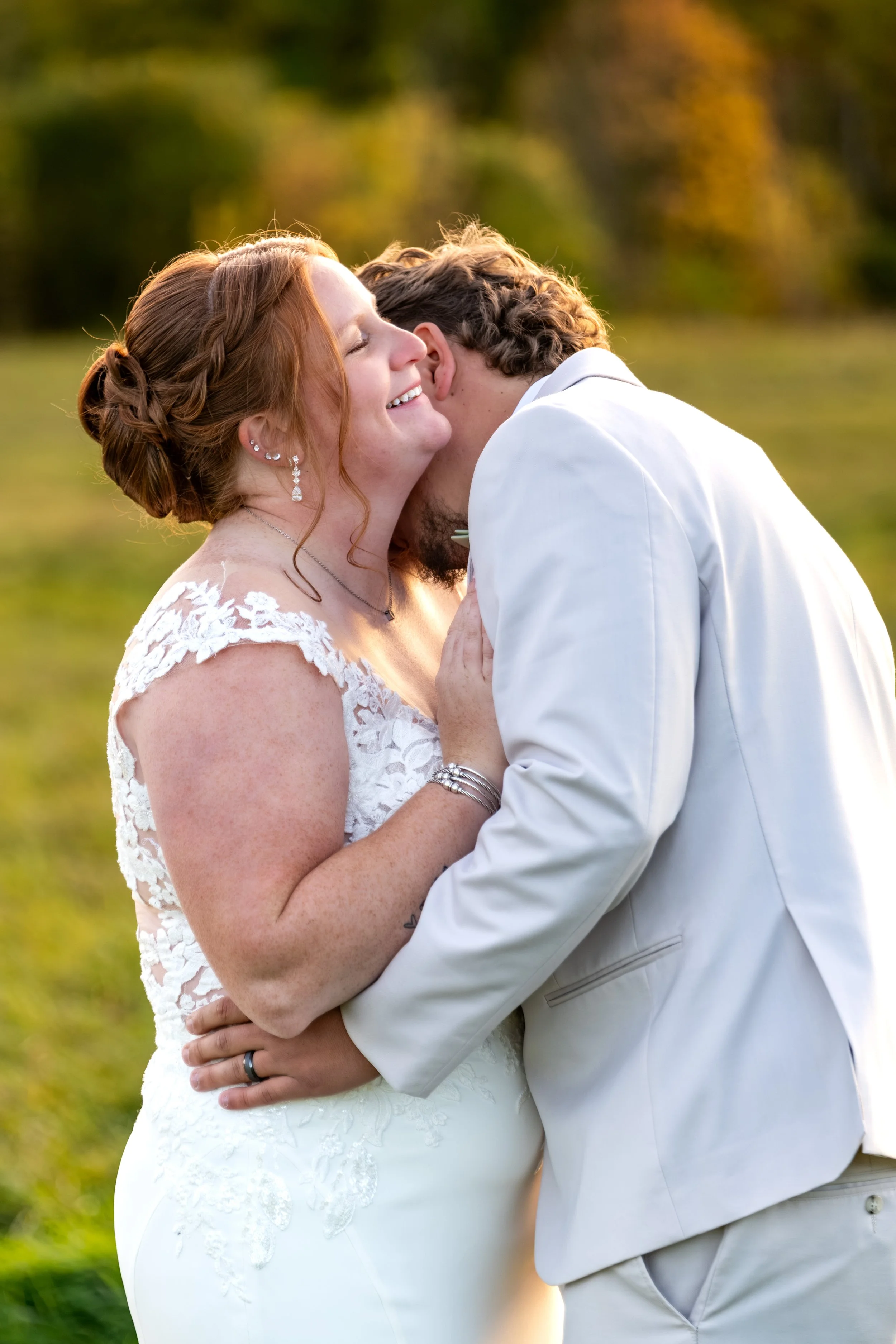 Erika smiling with her eyes closed as Andrew holds her close in the sunset at the Maine Wedding Barn and Event Center in Minot Maine fall wedding photography VMG Productions