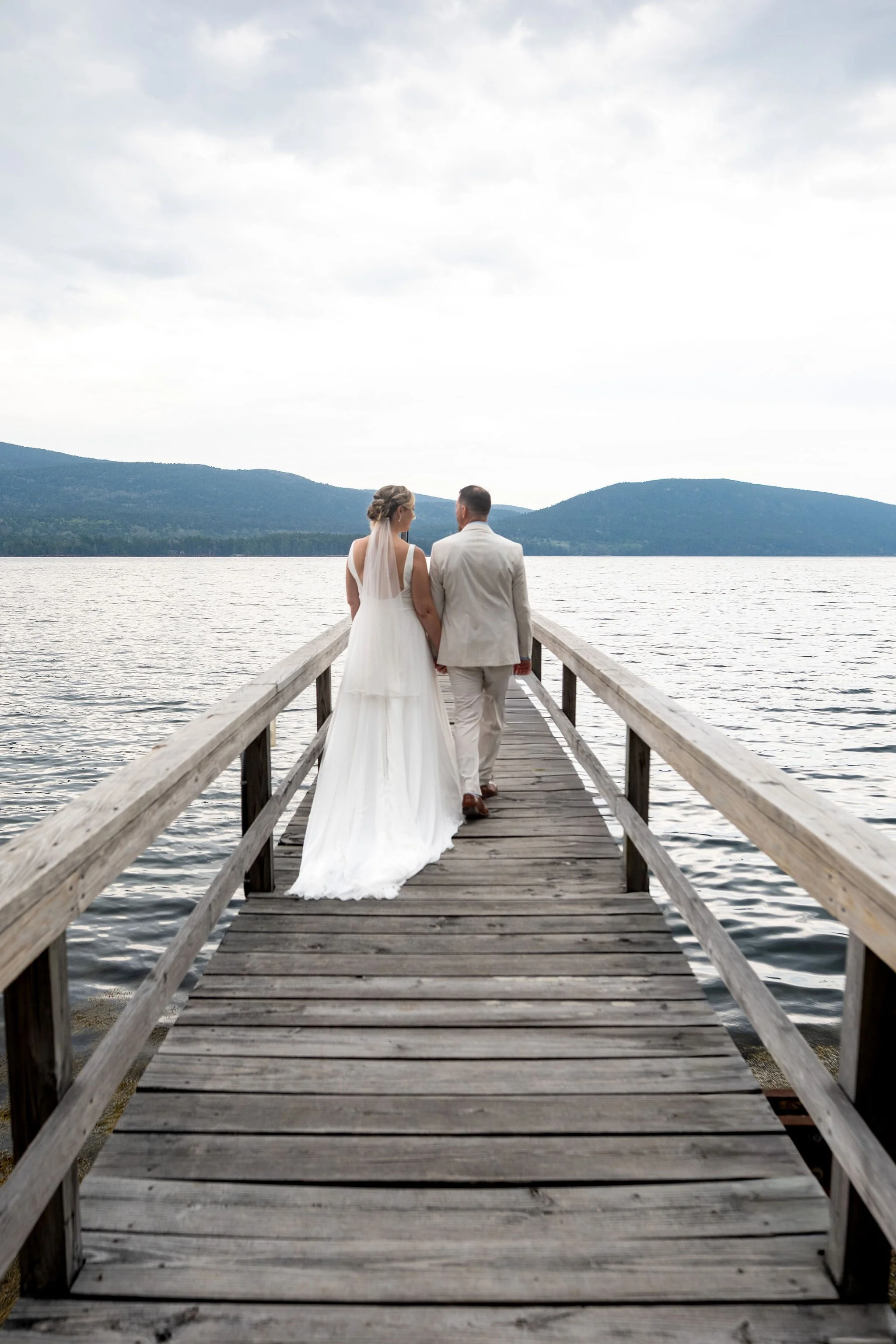 Alli and Adam Baudoin walking out the wooden dock over Somes Sound at their Mount Desert Maine private residence spring wedding photography VMG Productions