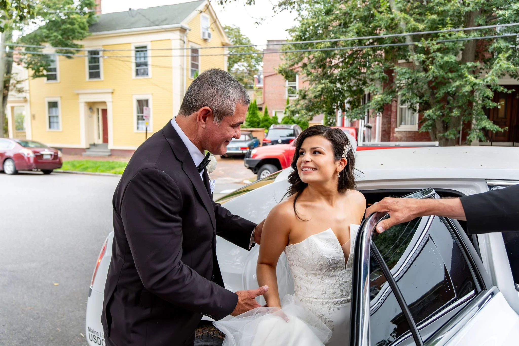 Alexey helping Nicole into their limousine outside Holy Trinity Greek Orthodox Church Portland Maine summer wedding photography VMG Productions