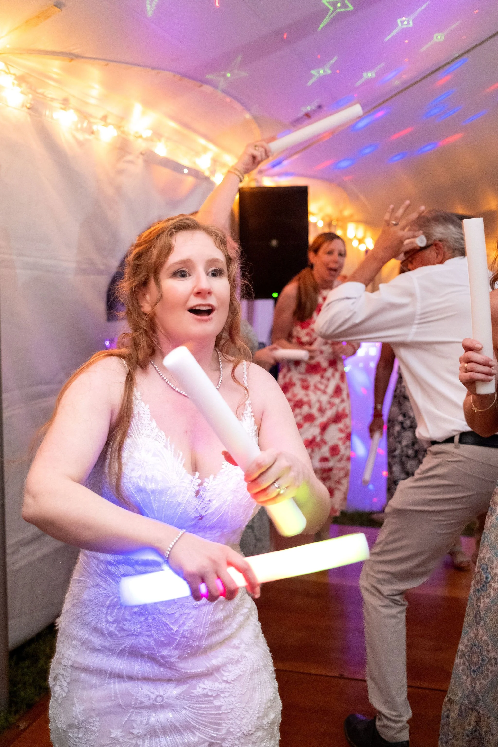Kayla DeAngelis mid-dance with glow sticks inside the reception tent at their Sanbornton New Hampshire wedding photography VMG Productions