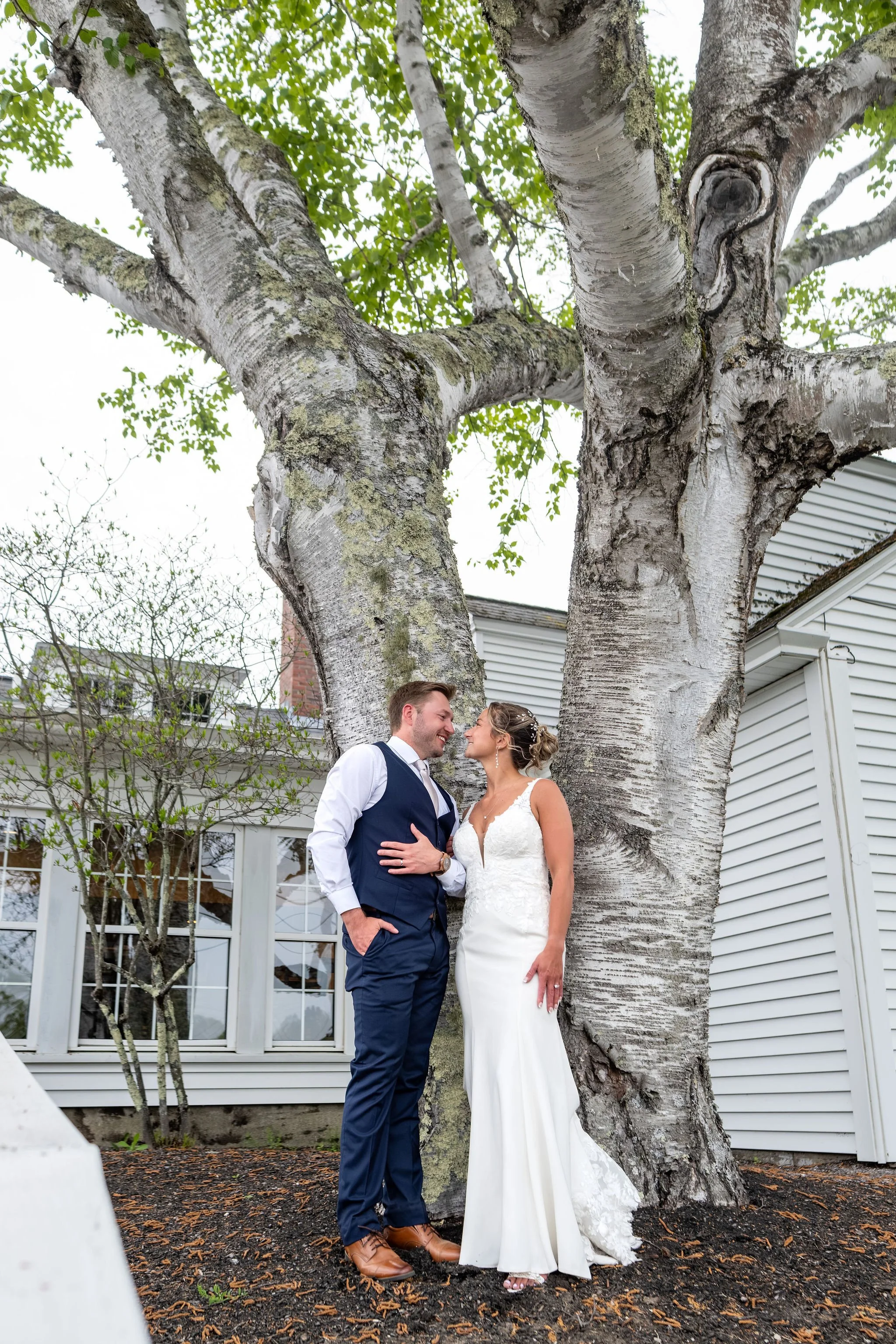 Beth and Cameron bride and groom beneath the birch tree near the clubhouse at Augusta Country Club Manchester Maine spring wedding photography VMG Productions