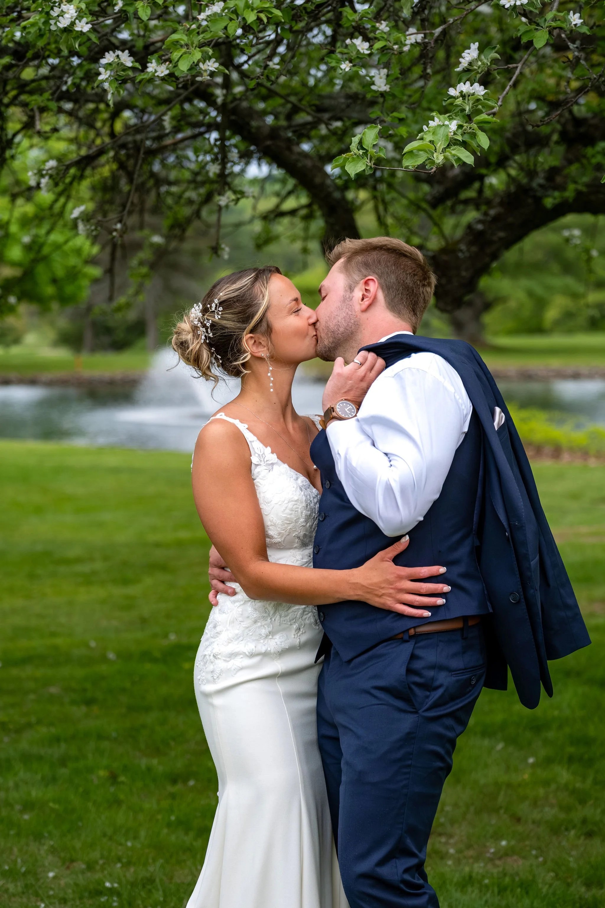 Beth and Cameron bride and groom kissing beneath spring blossoms at Augusta Country Club Manchester Maine spring wedding photography VMG Productions