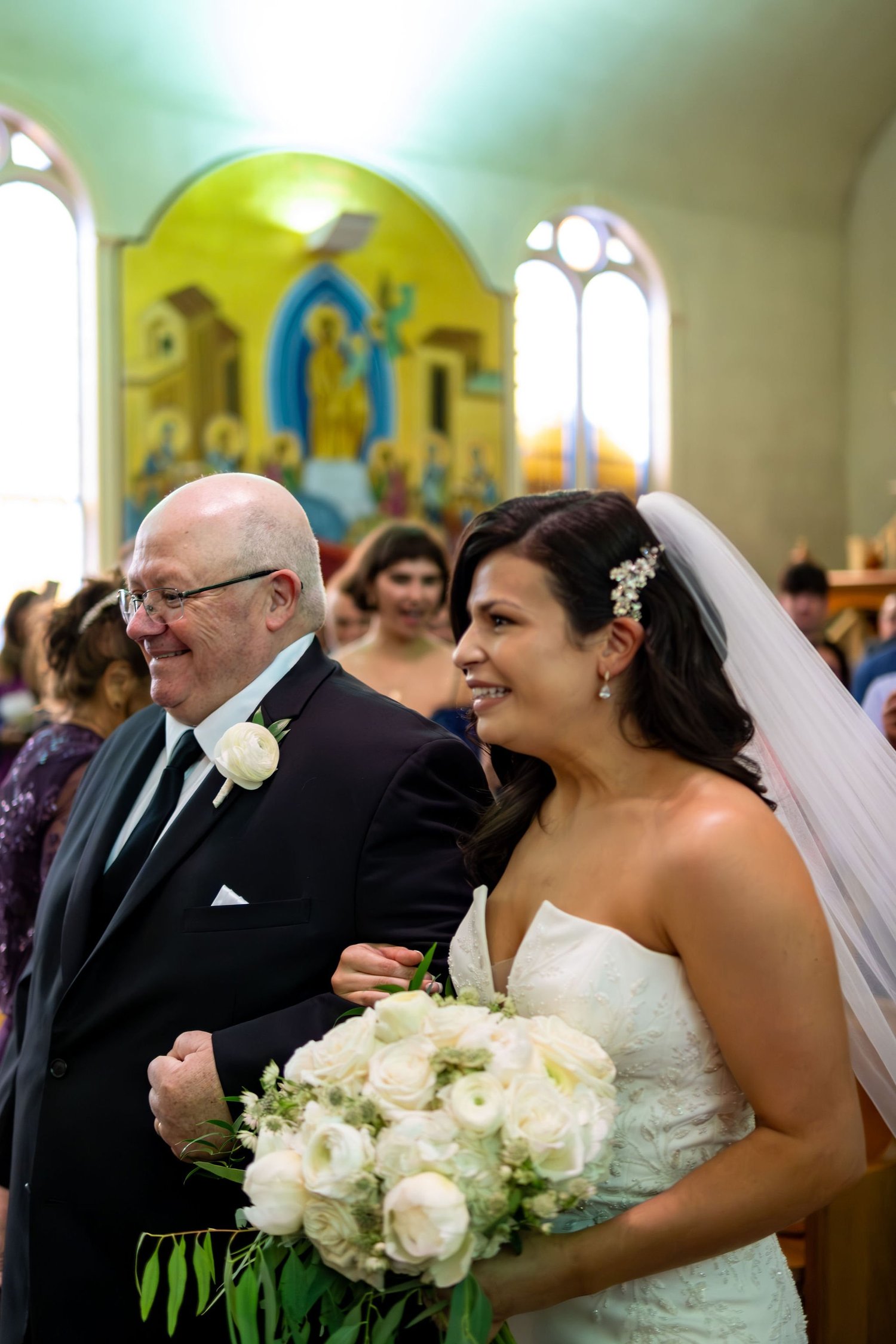 Nicole on her father's arm approaching the altar at Holy Trinity Greek Orthodox Church Portland Maine summer wedding photography VMG Productions