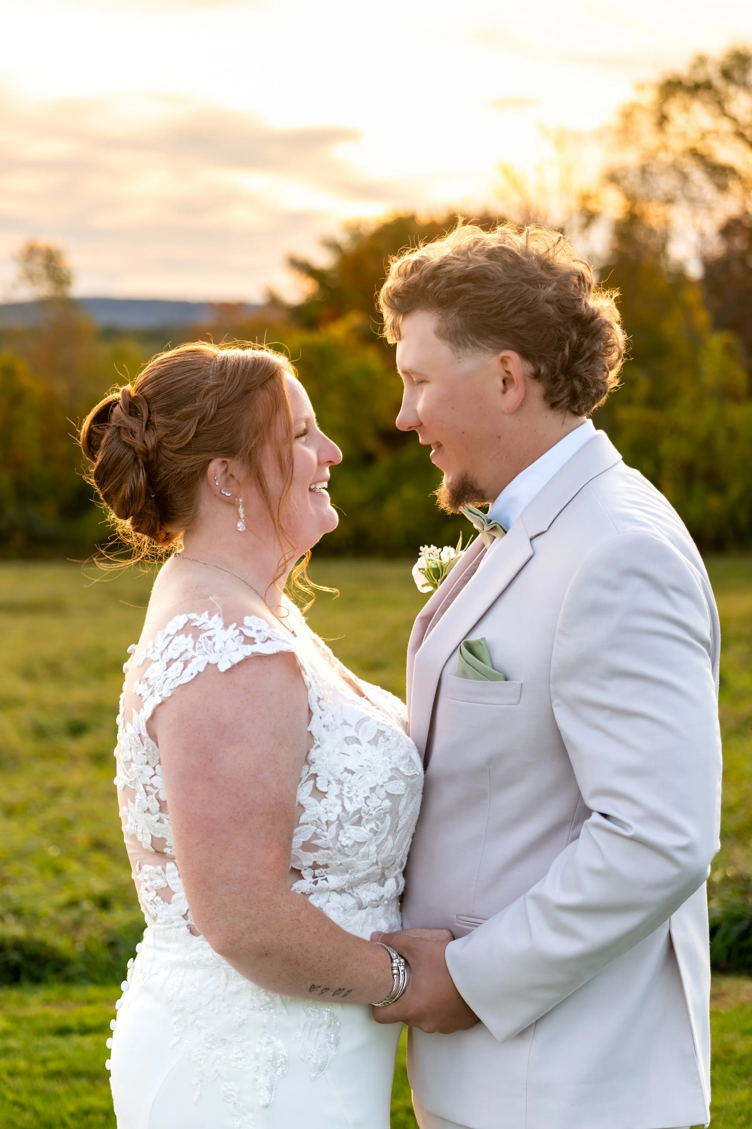 Erika and Andrew laughing together in the golden light with the foliage soft behind them at the Maine Wedding Barn and Event Center in Minot Maine fall wedding photography VMG Productions