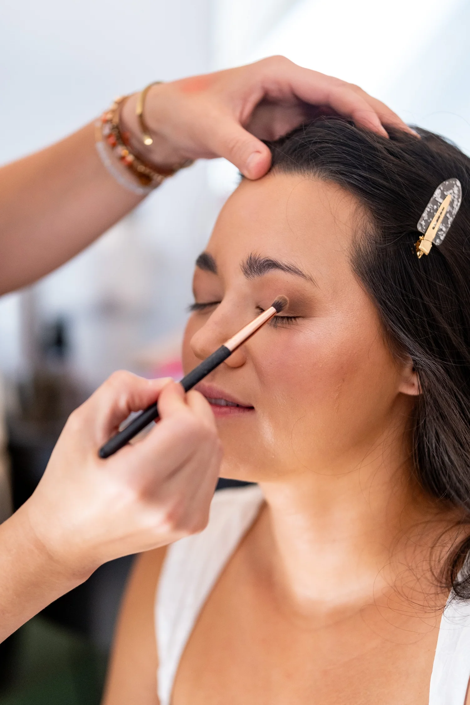 Makeup artist applying eyeshadow to bride during wedding morning preparation at The Inn on Peaks Island Portland Maine