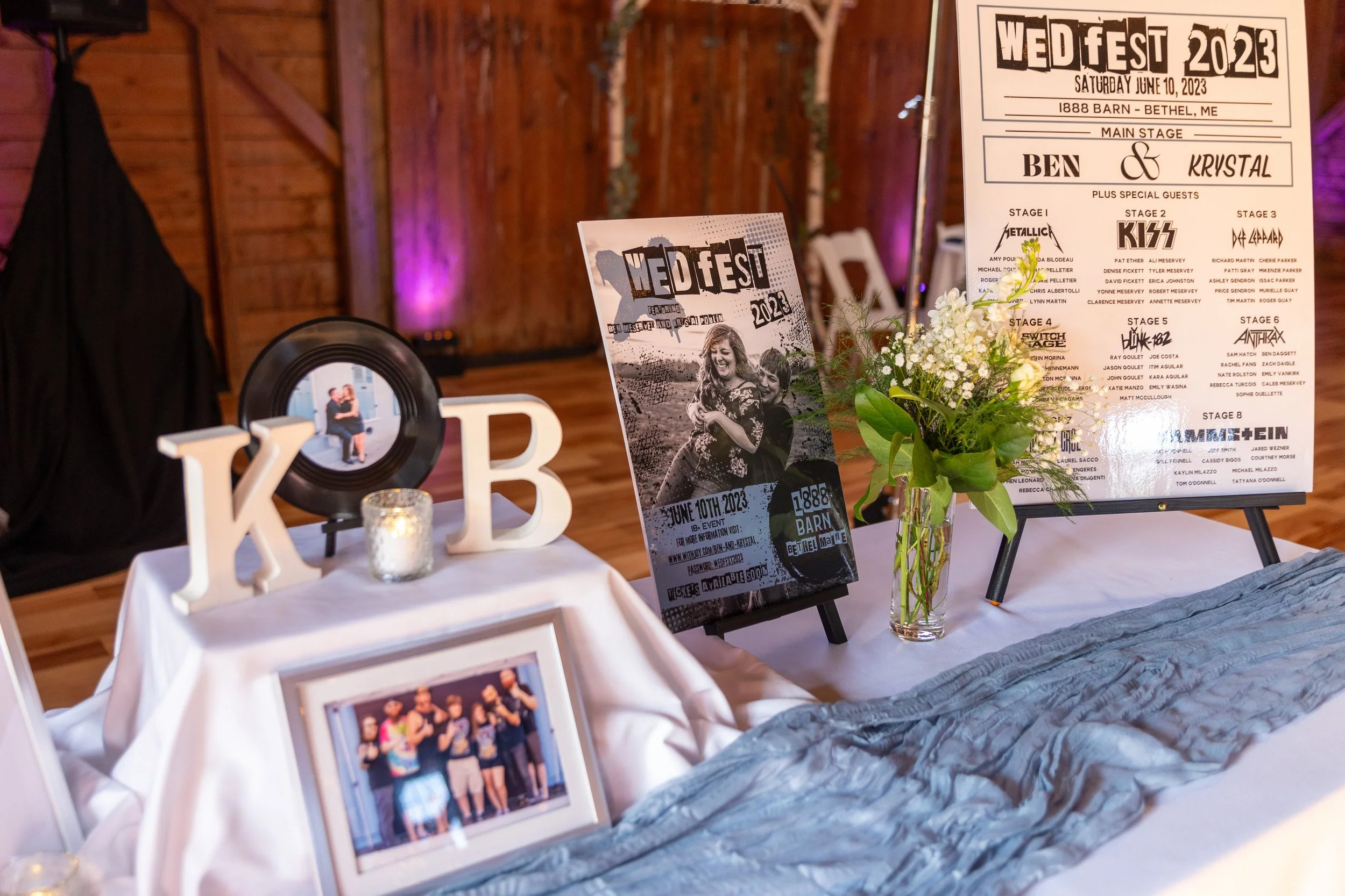 WEDFEST 2023 themed wedding reception table at 1888 Wedding Barn Bethel Maine with festival lineup poster listing all guests as performers vinyl record couple photo display wooden card chest and floral arrangement for Krystal and Ben June 2023