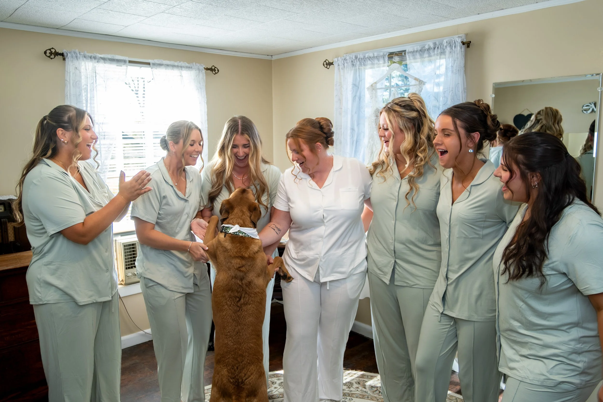 Erika and her bridesmaids in a circle with Penny the dog in the middle at the Maine Wedding Barn and Event Center in Minot Maine fall wedding photography VMG Productions