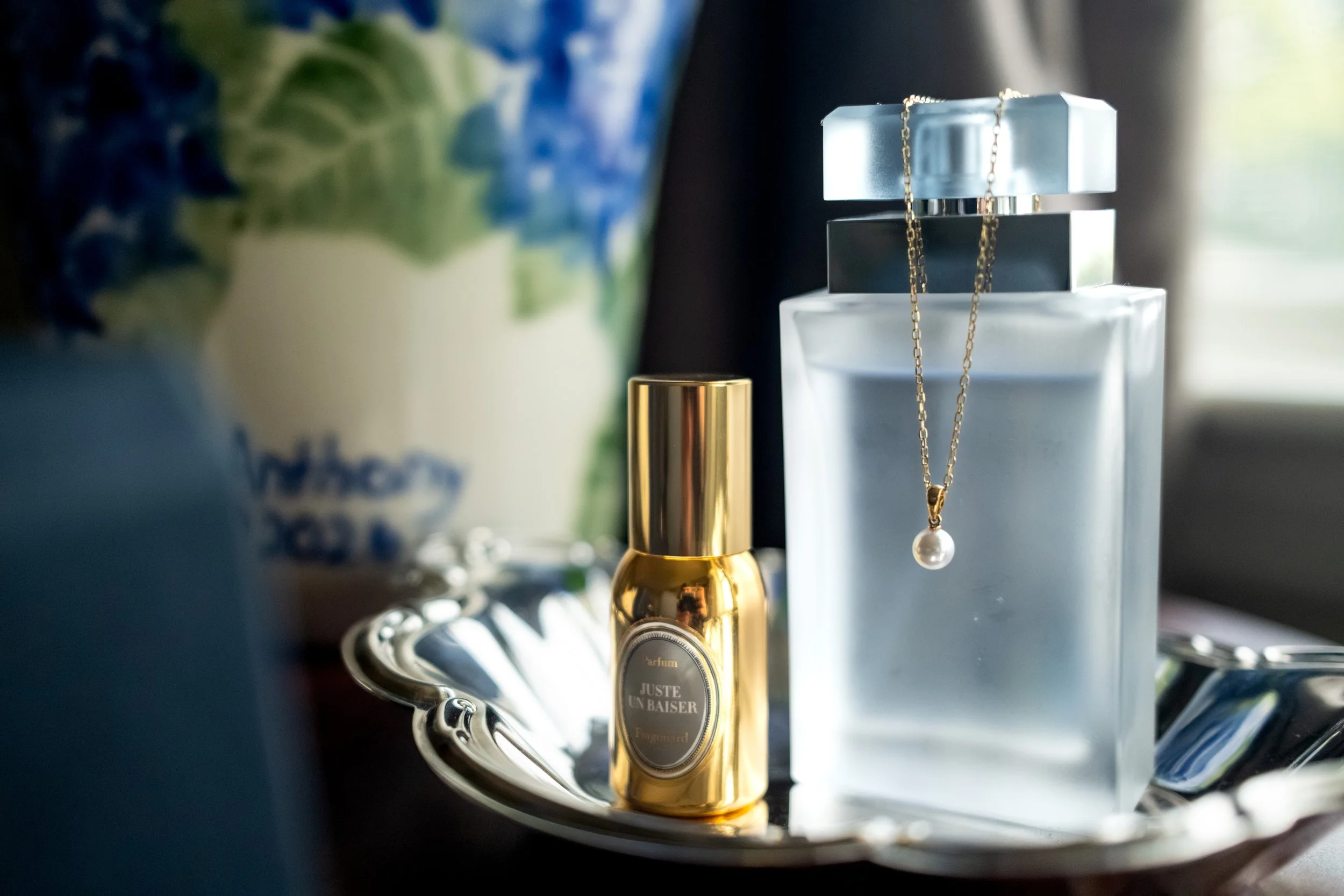 Fragonard Juste Un Baiser perfume with pearl necklace and blue hydrangea vase on a silver tray in the bridal suite at Union Bluff Hotel in York Maine wedding photography VMG Productions