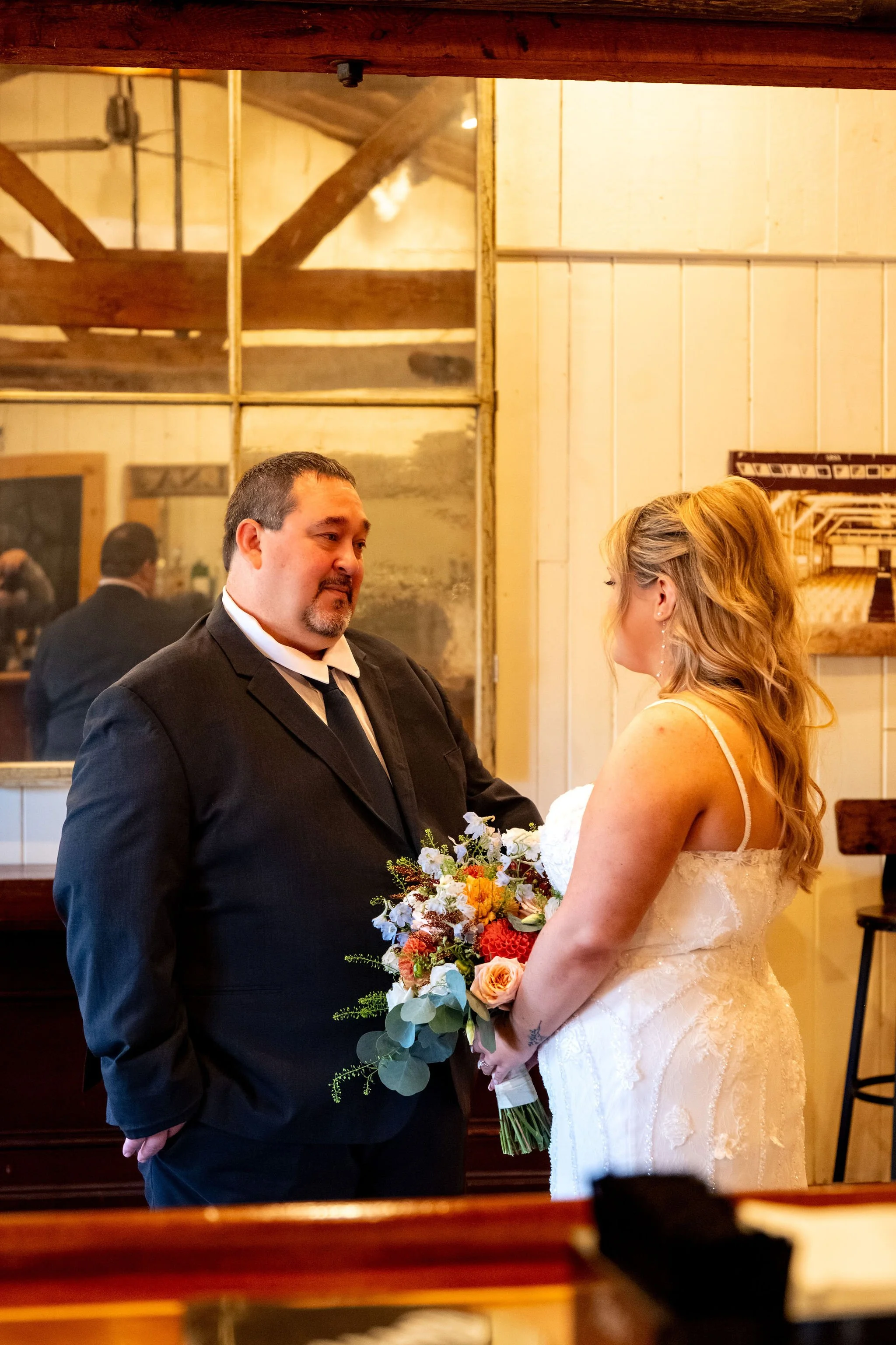 Ellie and her dad sharing a moment with the barn's windows and beams behind them at Boothbay Playhouse in Boothbay Maine fall wedding photography VMG Productions