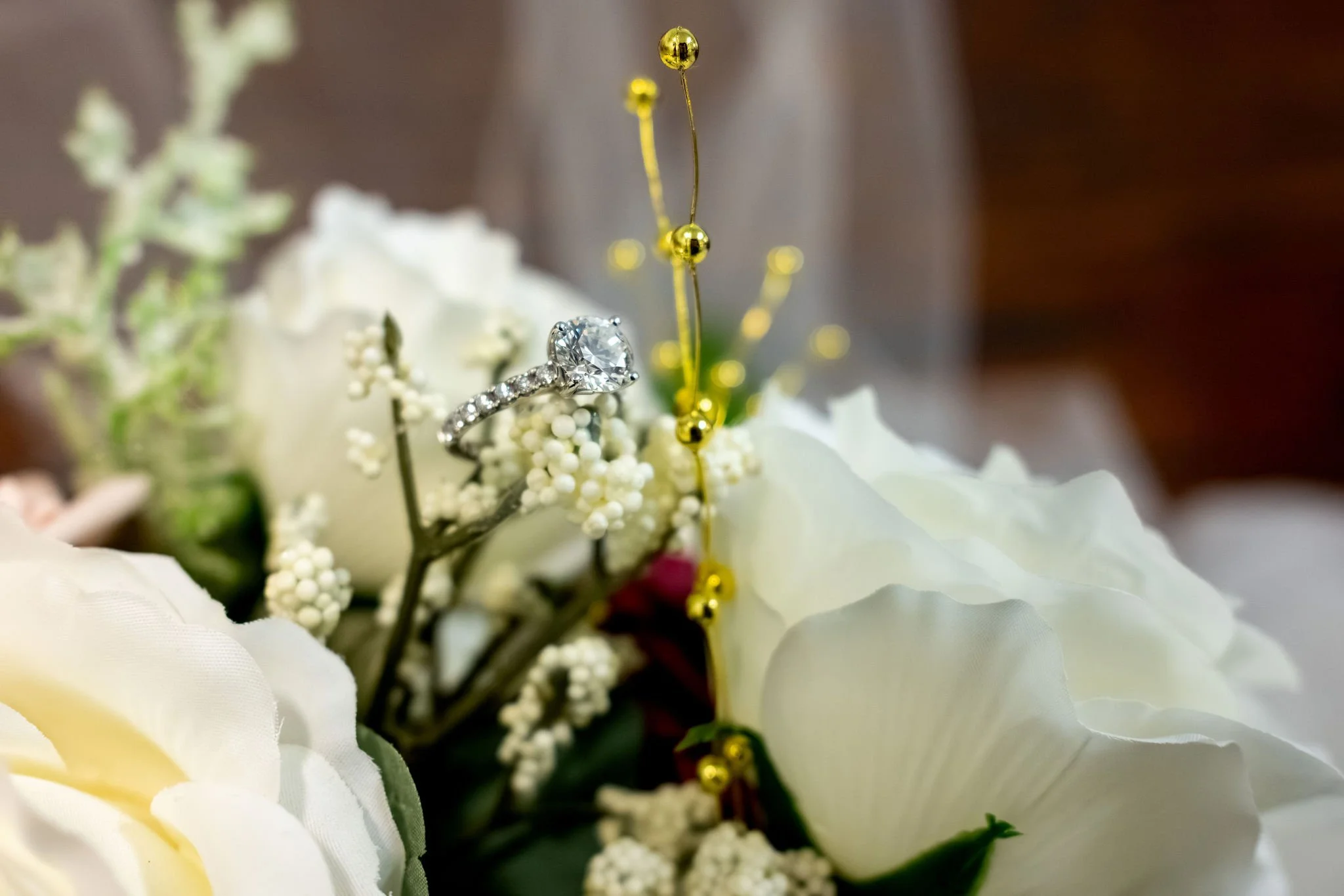 Jeremiah and Vienna close-up composition featuring engagement ring nestled among bouquet florals at Holy Trinity Greek Orthodox Church Portland Maine spring wedding photography VMG Productions