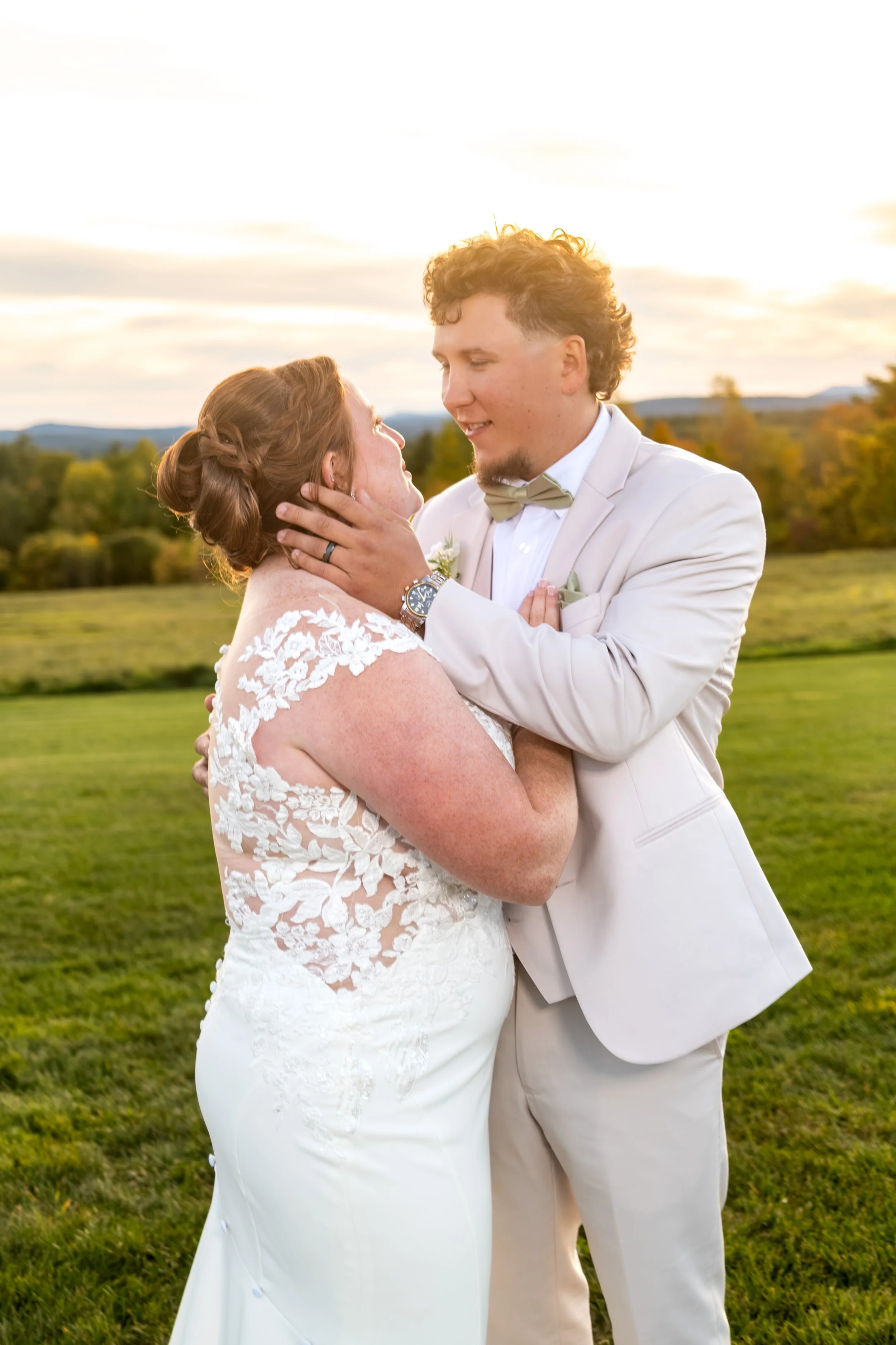 Erika holding Andrew's face as the sunset glows behind them at the Maine Wedding Barn and Event Center in Minot Maine fall wedding photography VMG Productions