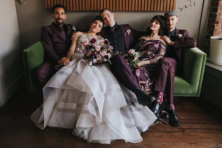 Five people pose on a couch on a wedding day.