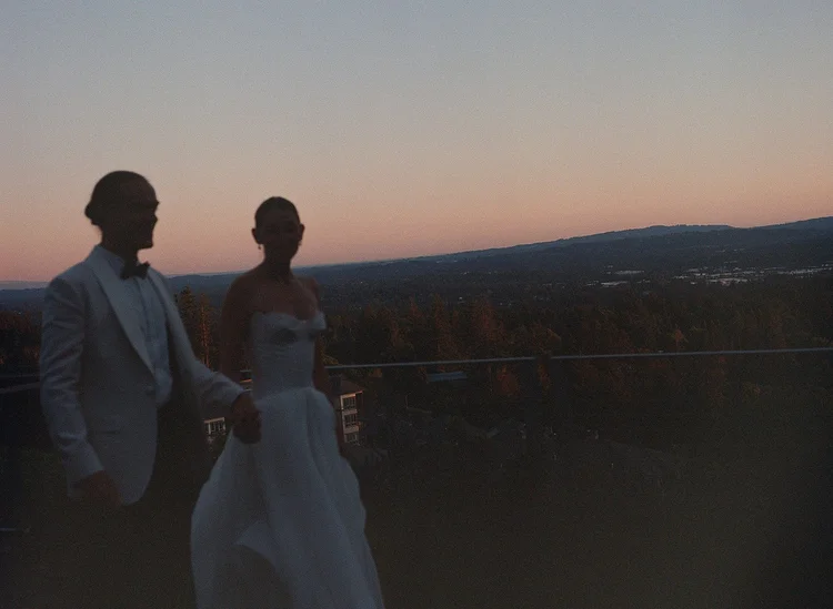 A bride and groom walk at sunset on their wedding day.