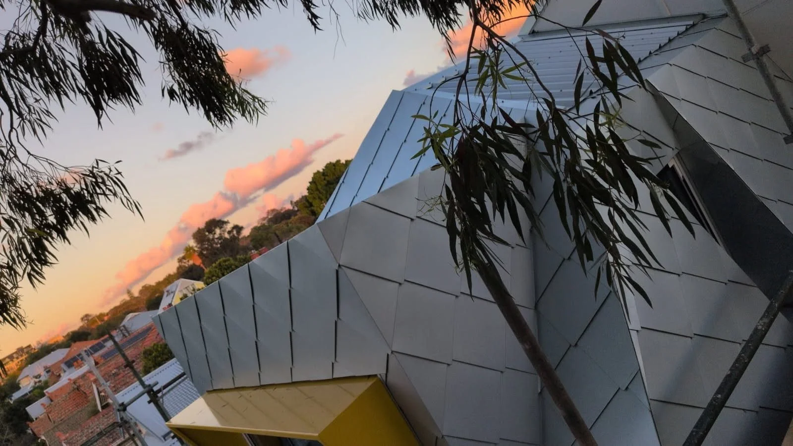 Diamond metal shingle cladding at sunset during construction