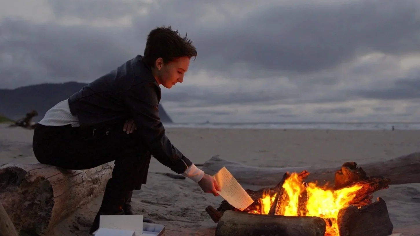 Still from the 2025 cinematography reel, a figure lighting a beach fire at dusk
