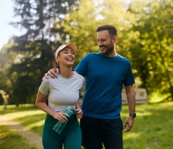Happy active couple walking together outside and smiling indicating successful Del City pain management care.