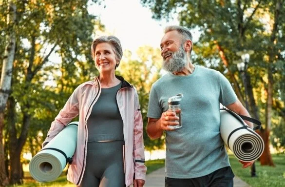 Happy active older couple walking together and smiling with successful Remington pain management care
