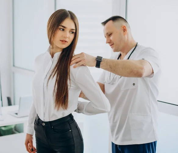 Car accident doctor in Norman examining female patient with back pain