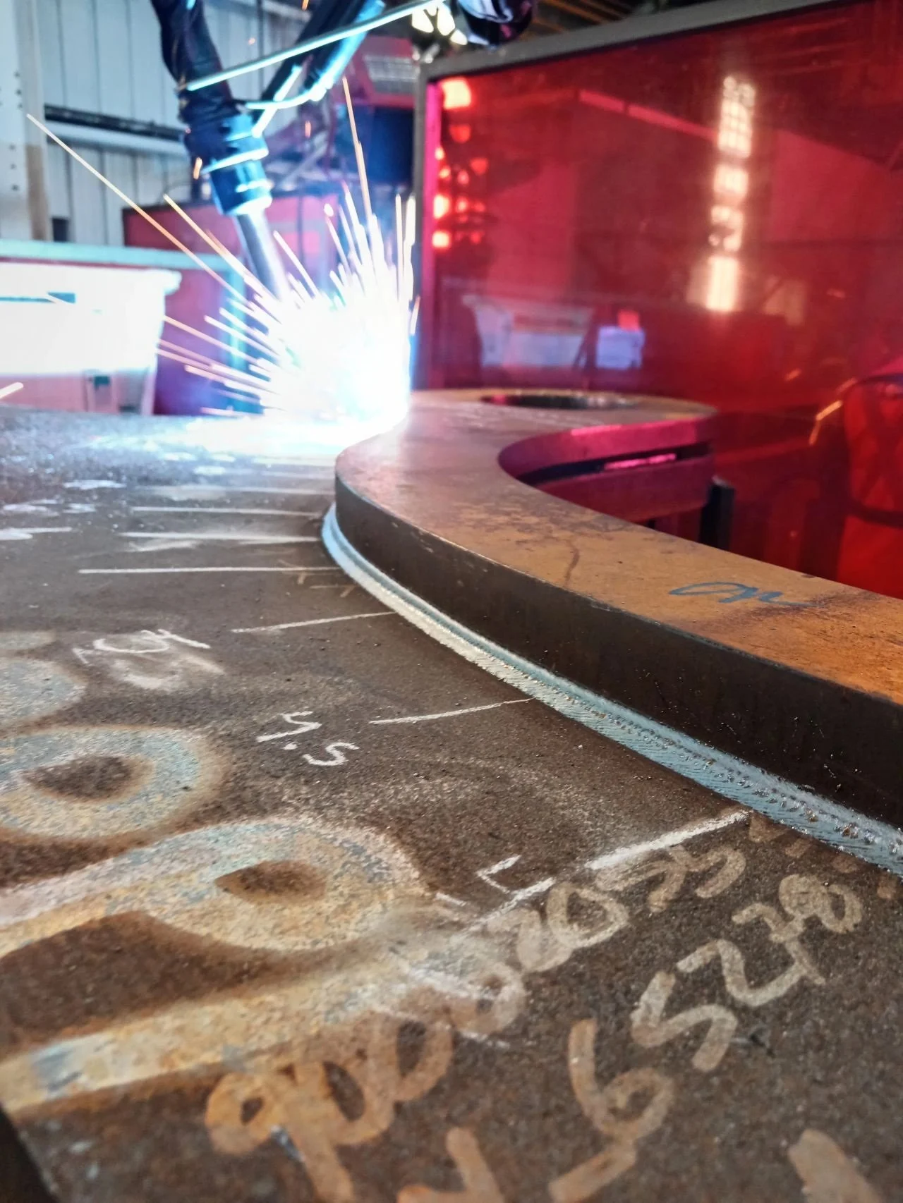 Automated welding robot performing precision welding on thick steel equipment component in an industrial equipment manufacturing environment.