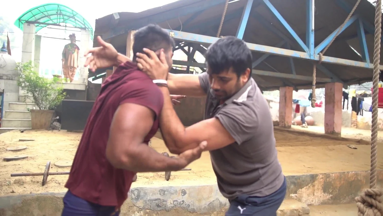 Two wrestlers grip in the courtyard