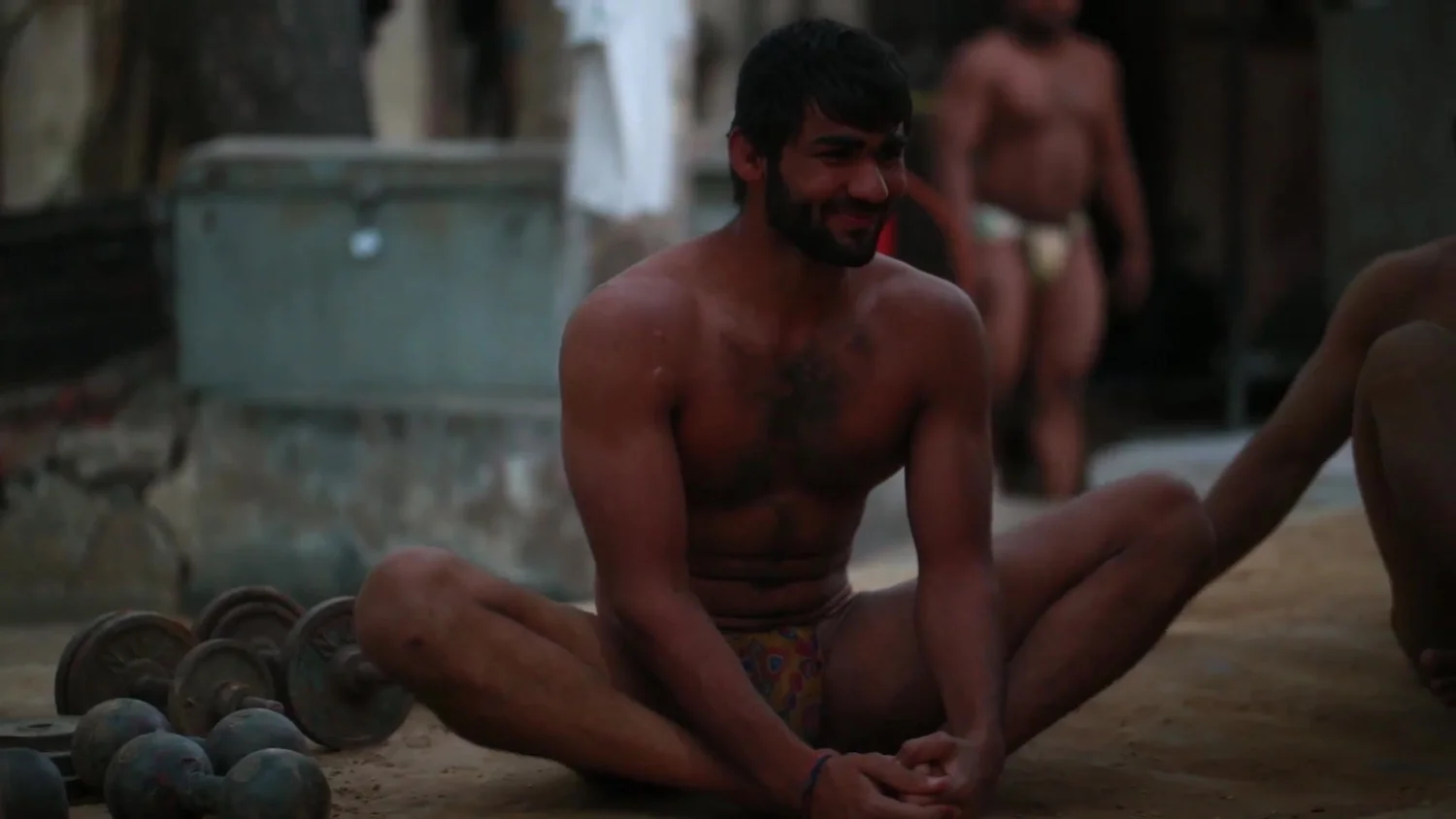 A wrestler sits in the pit after training