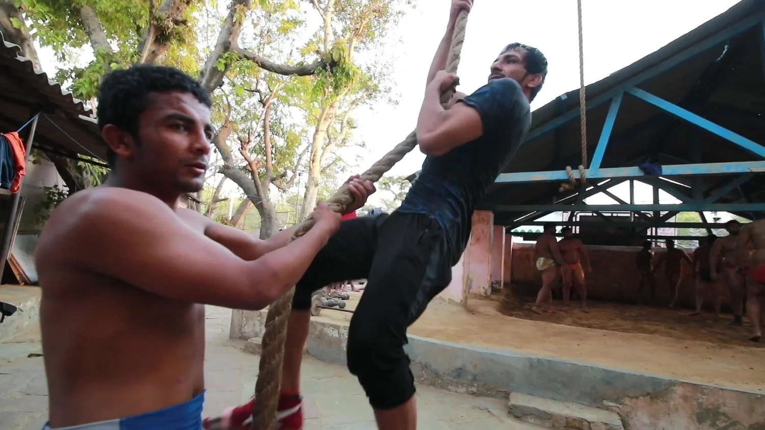 A wrestler climbs the rope in the courtyard