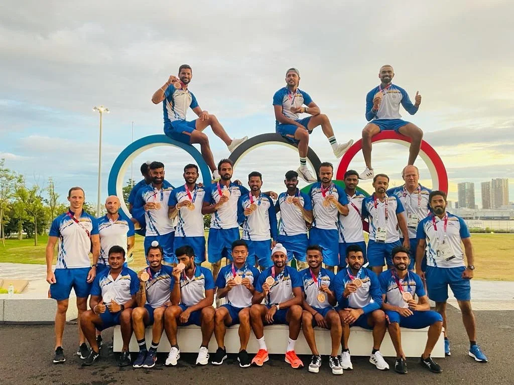 India's Tokyo 2020 hockey squad with their bronze medals at the Olympic rings