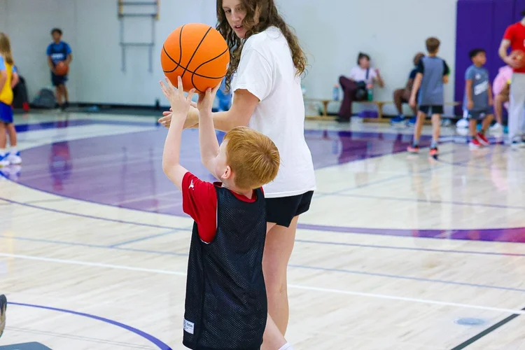Coach Iris Sylvester helping a young Junior Coyotes player with his shot