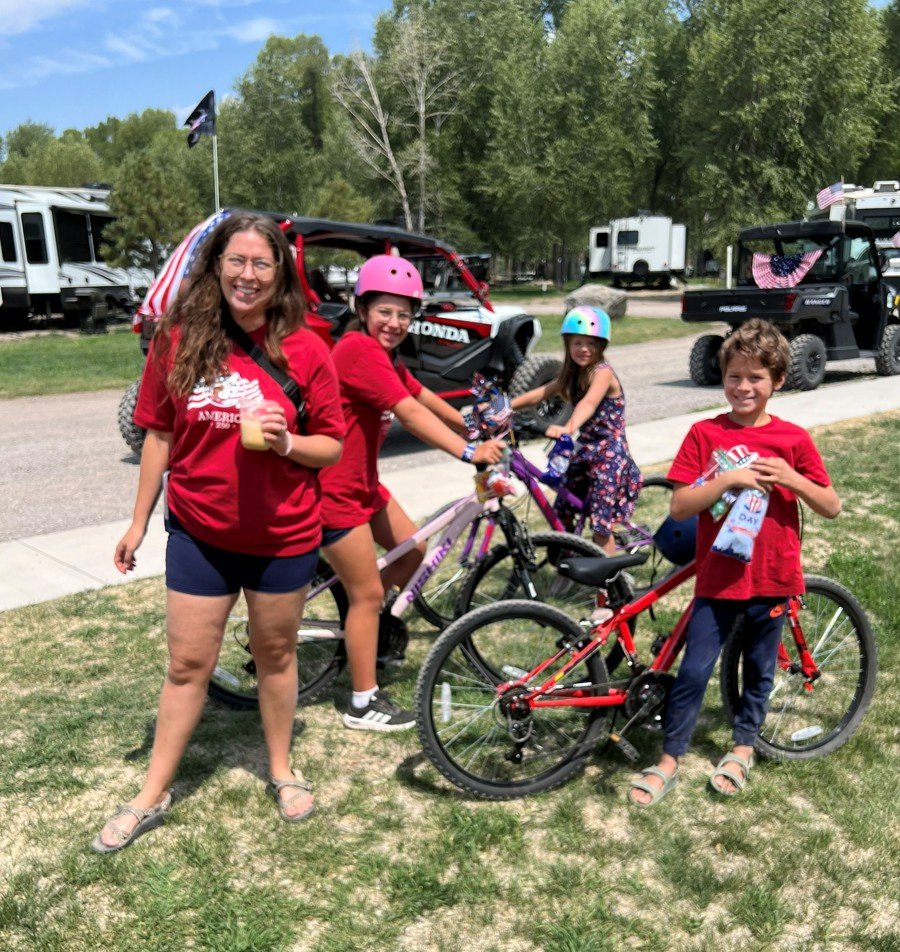 Guests smiling with bicycles on the campground lawn.