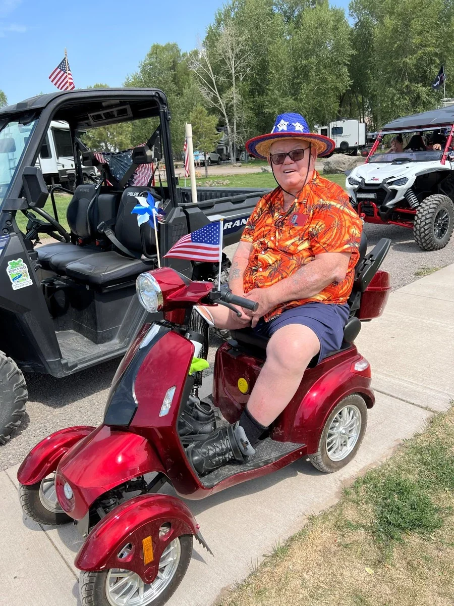 A guest smiling on a red mobility scooter.