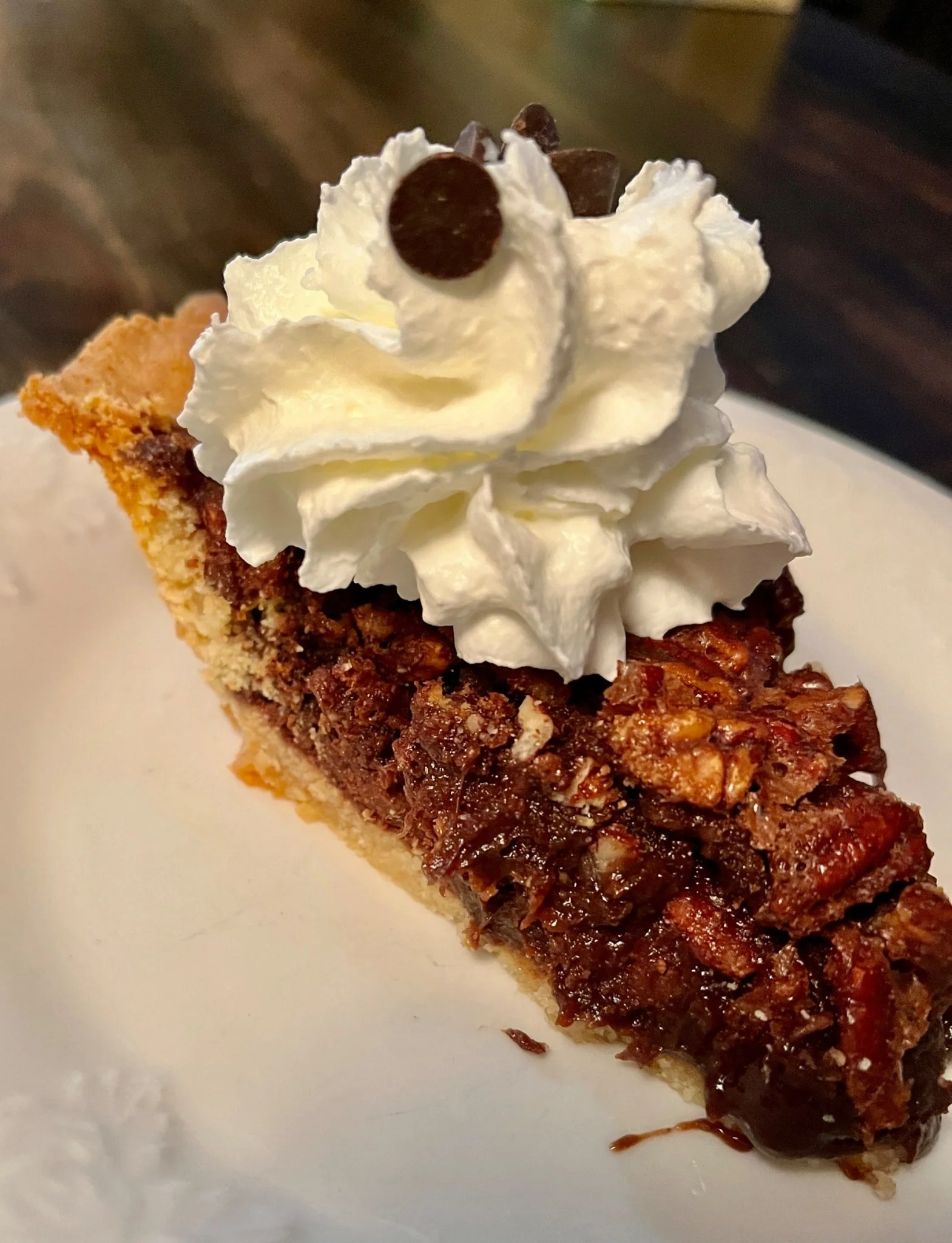 Slice of pecan pie topped with whipped cream.