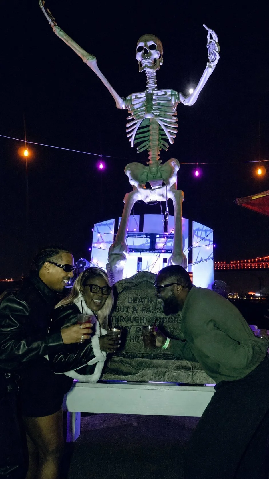 Guests posing with the giant skeleton at Haunted Pier on Cavanaugh's River Deck