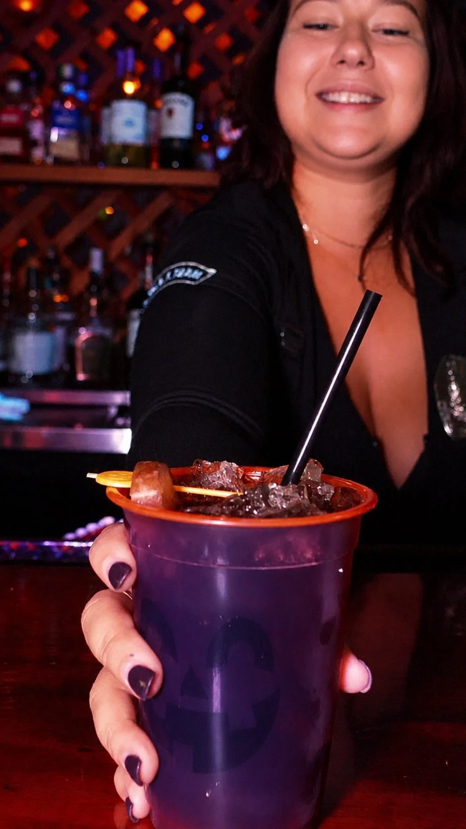 Bartender serving a Halloween cocktail in a jack-o'-lantern cup
