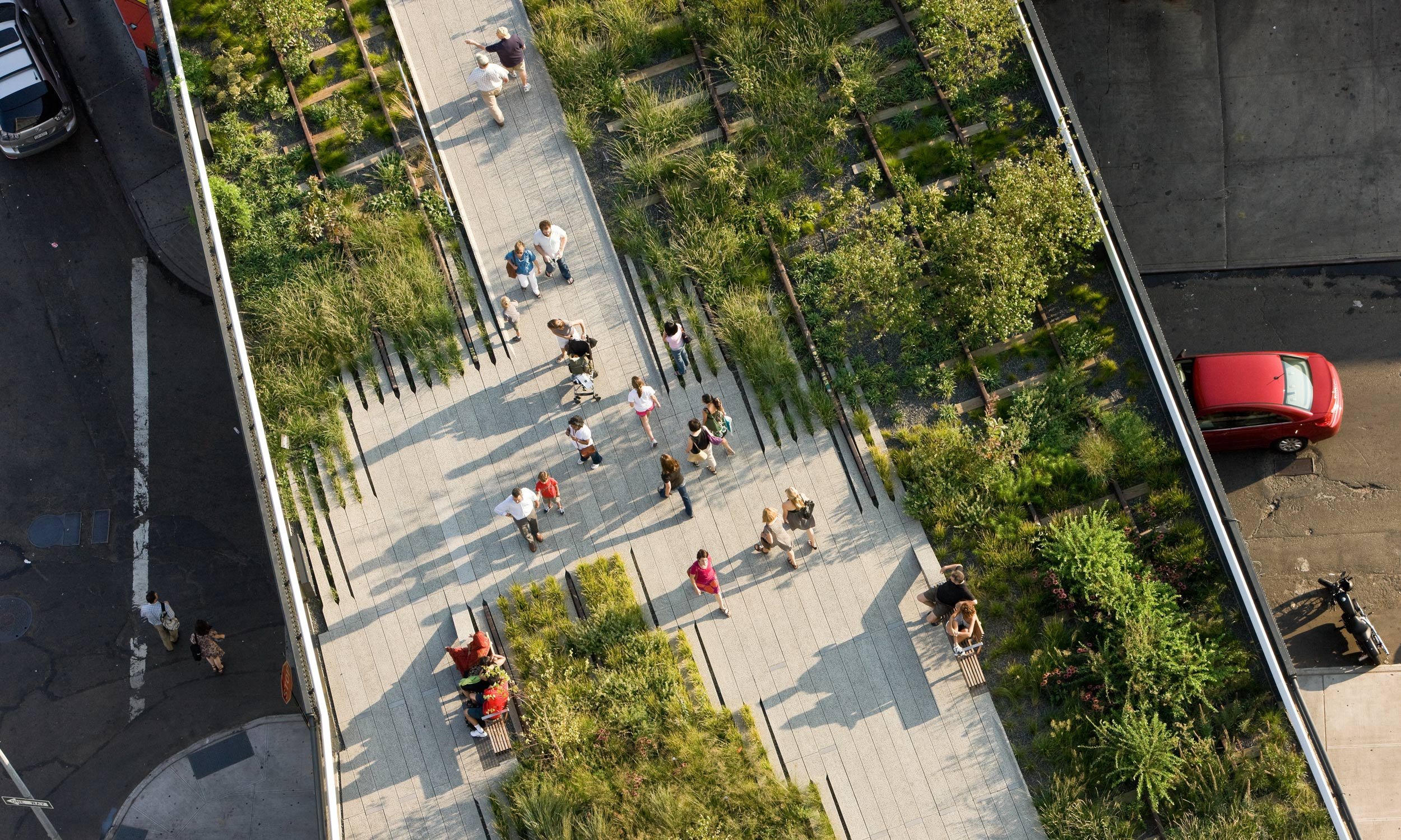 Aerial view of a green walkway in an open space, with people strolling along the path of the High Line.