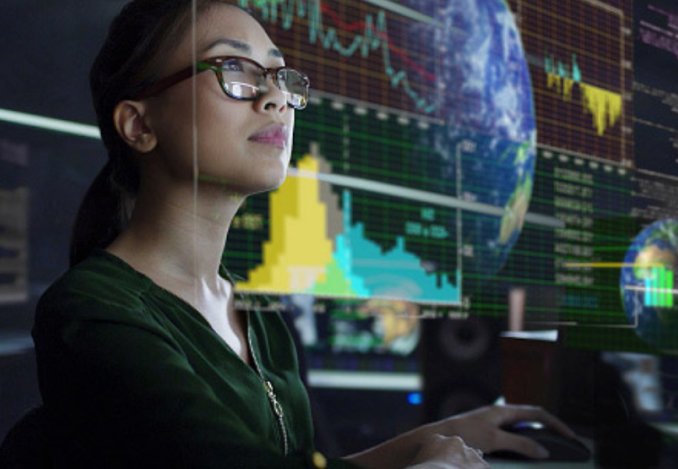 A woman wearing glasses gazes intently at a computer screen, focused on her work or research. Cybersecurity Workforce Development NYCEDC - New York, NY