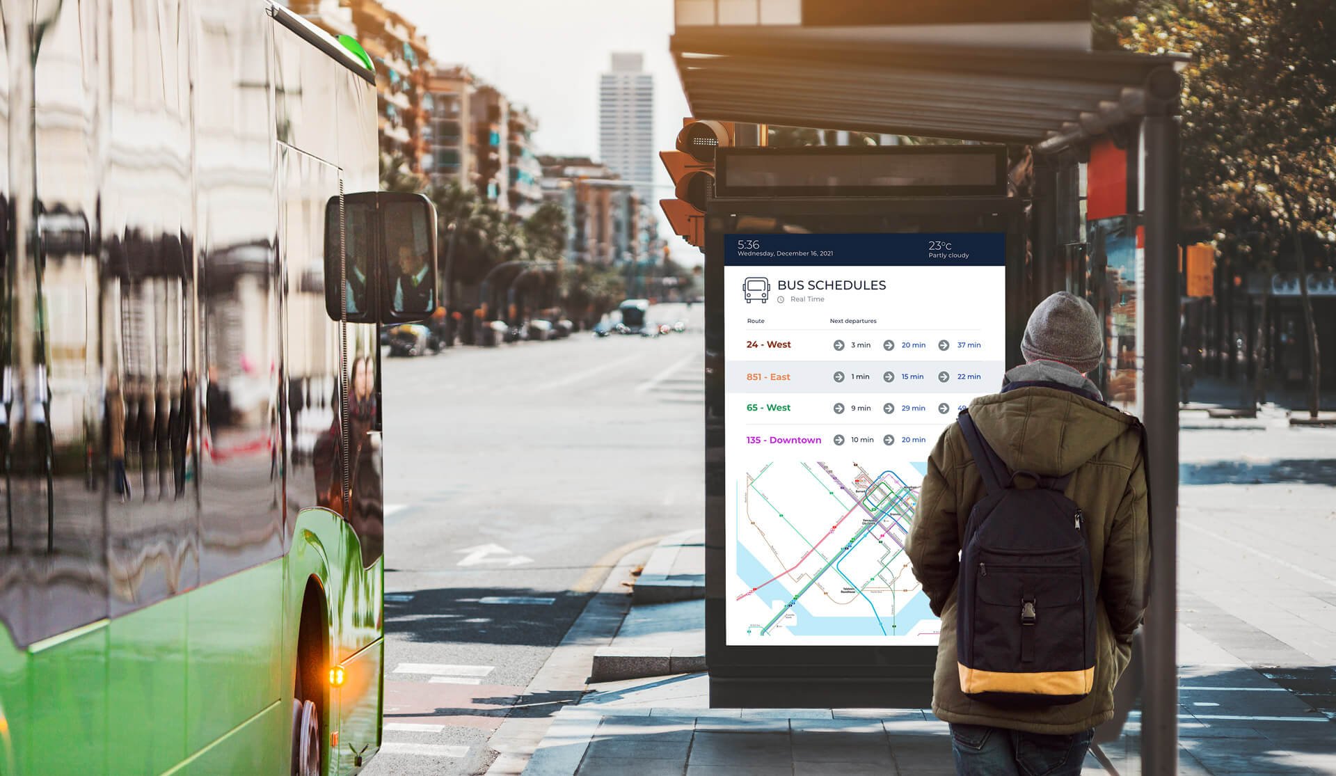 A man stands at a bus stop, with a bus and modern technology visible in the background.