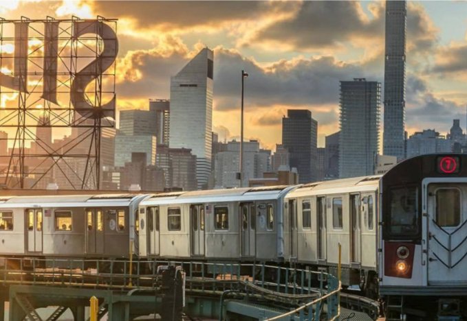 A subway train moves through the city as the sun sets, casting warm hues across the skyline and tracks. NYC Subway NYC Mayor’s Office of Criminal Justice.